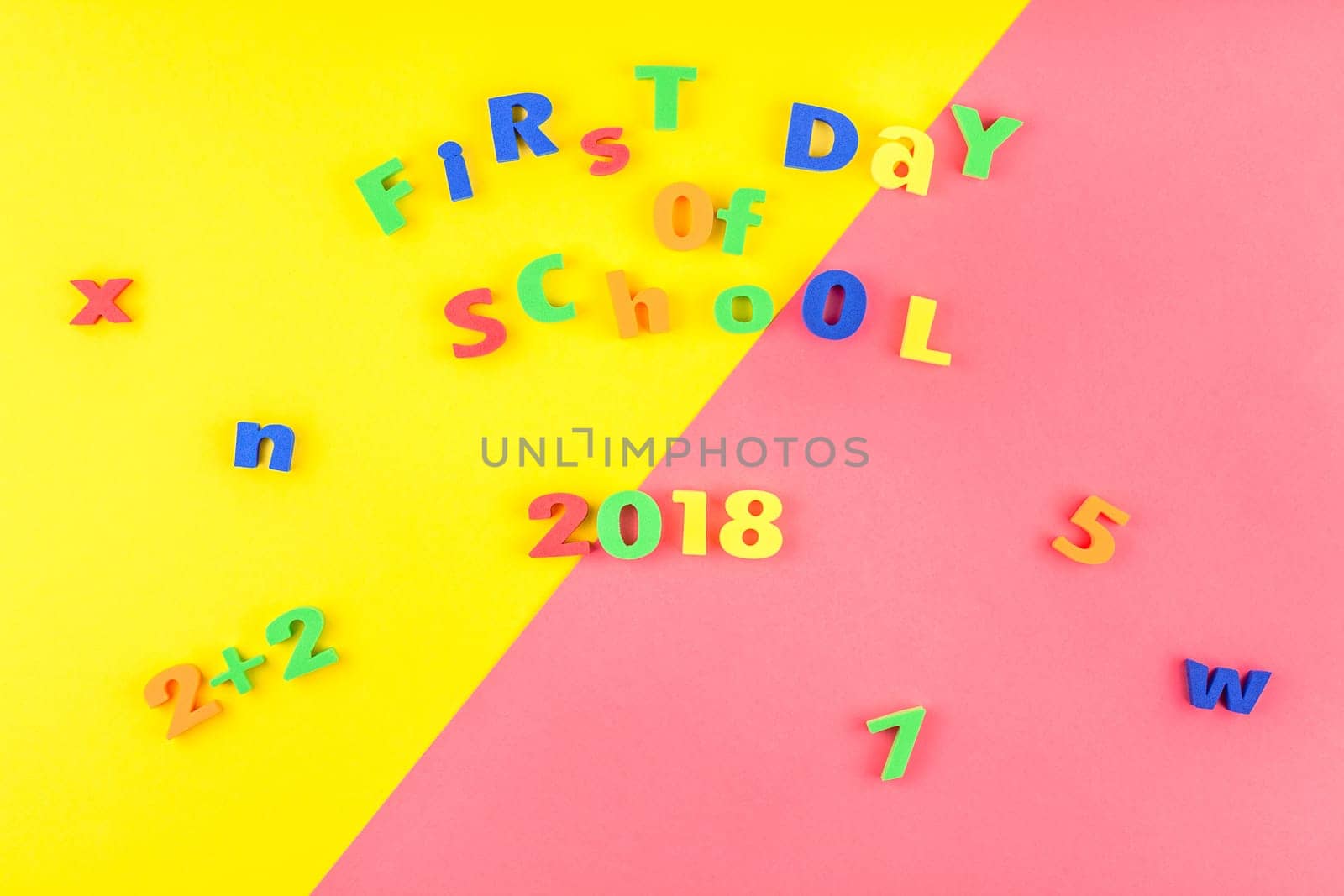 Creative flat lay back to school concept with welcome letters message on bright yellow and pink paper background with copy space, template for text or design