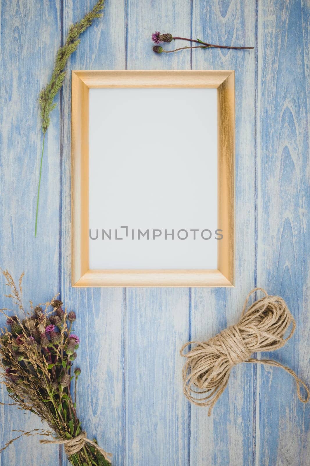 Top view of autumn orange pumpkins and dry flowers with grass thanksgiving background over blue toned wooden table with golden frame mock up and copy space in rustic style, template for text