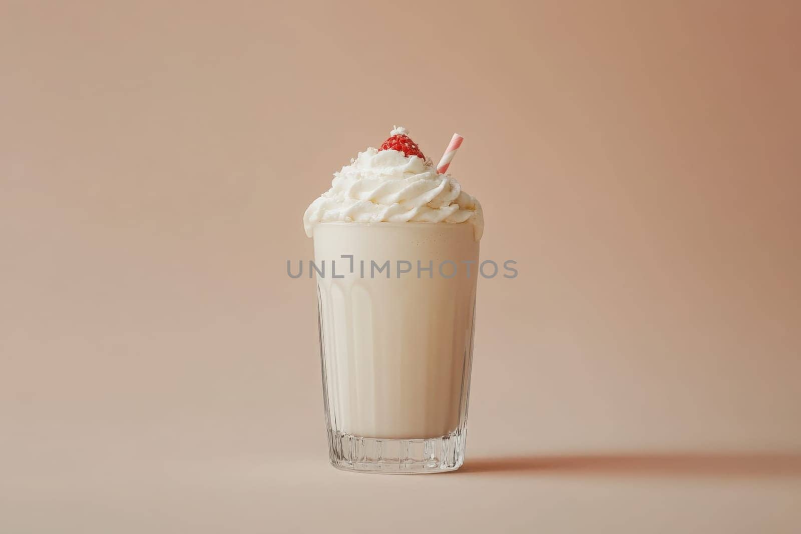 This minimalist milkshake glass filled with a creamy beverage is beautifully topped with whipped cream and a cherry. The soft background enhances its elegant presentation.