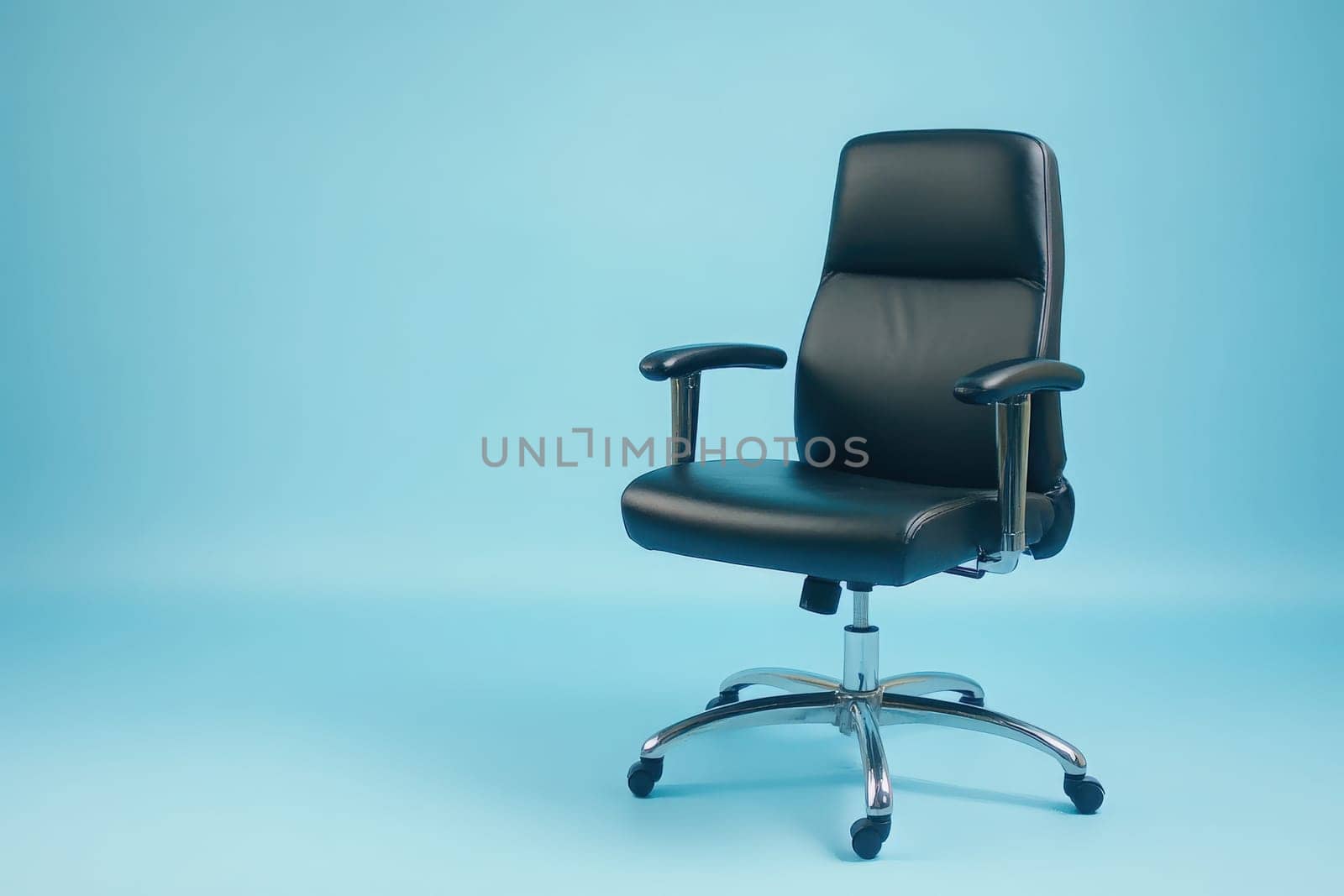 An office chair is pulled out to the side on a solid, clean surface, set against a calming light blue backdrop, creating an inviting workspace environment for productivity.