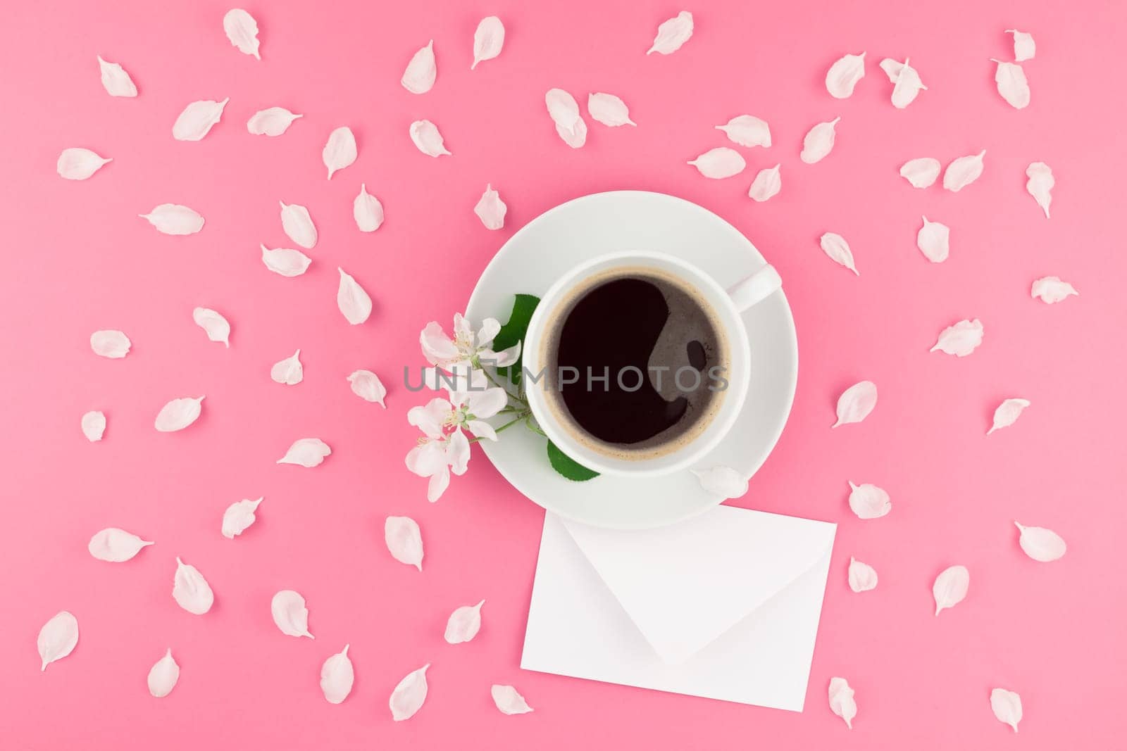 Creative flat lay concept top view of coffee cup and white apple tree flowers petals on pastel pink background with postcard mock up and copy space in minimal style, template for text