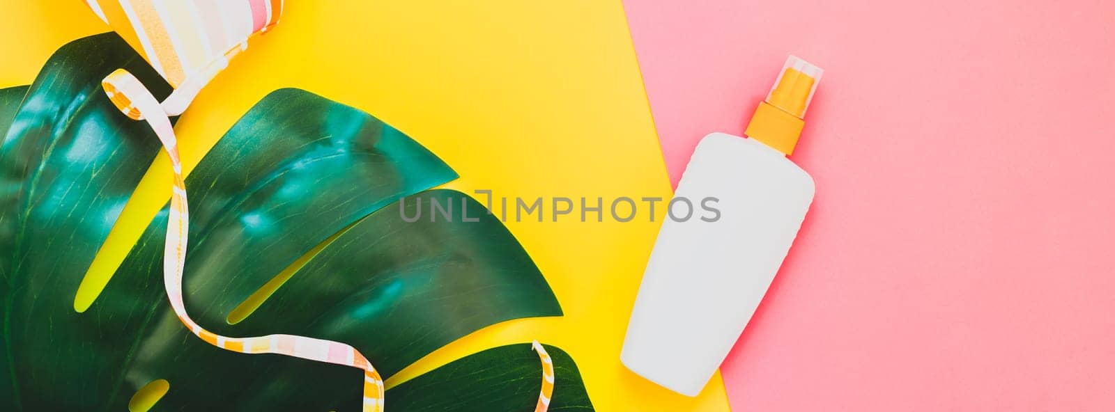 Tropical jungle palm monstera leaves, sunscreen blank bottle mockup and woman's swimsuit on bright color paper background. Summer vacations creative flat lay concept template text. Long wide banner