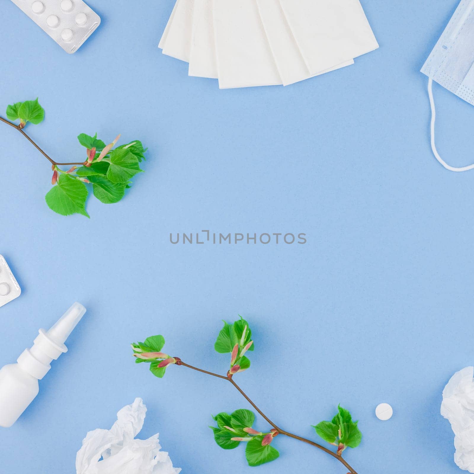 Creative flat lay concept of seasonal spring pollen allergy with napkins, pills, face mask, drops in a bottle and fresh green sprouts with buds. Square copy space background minimal style, template