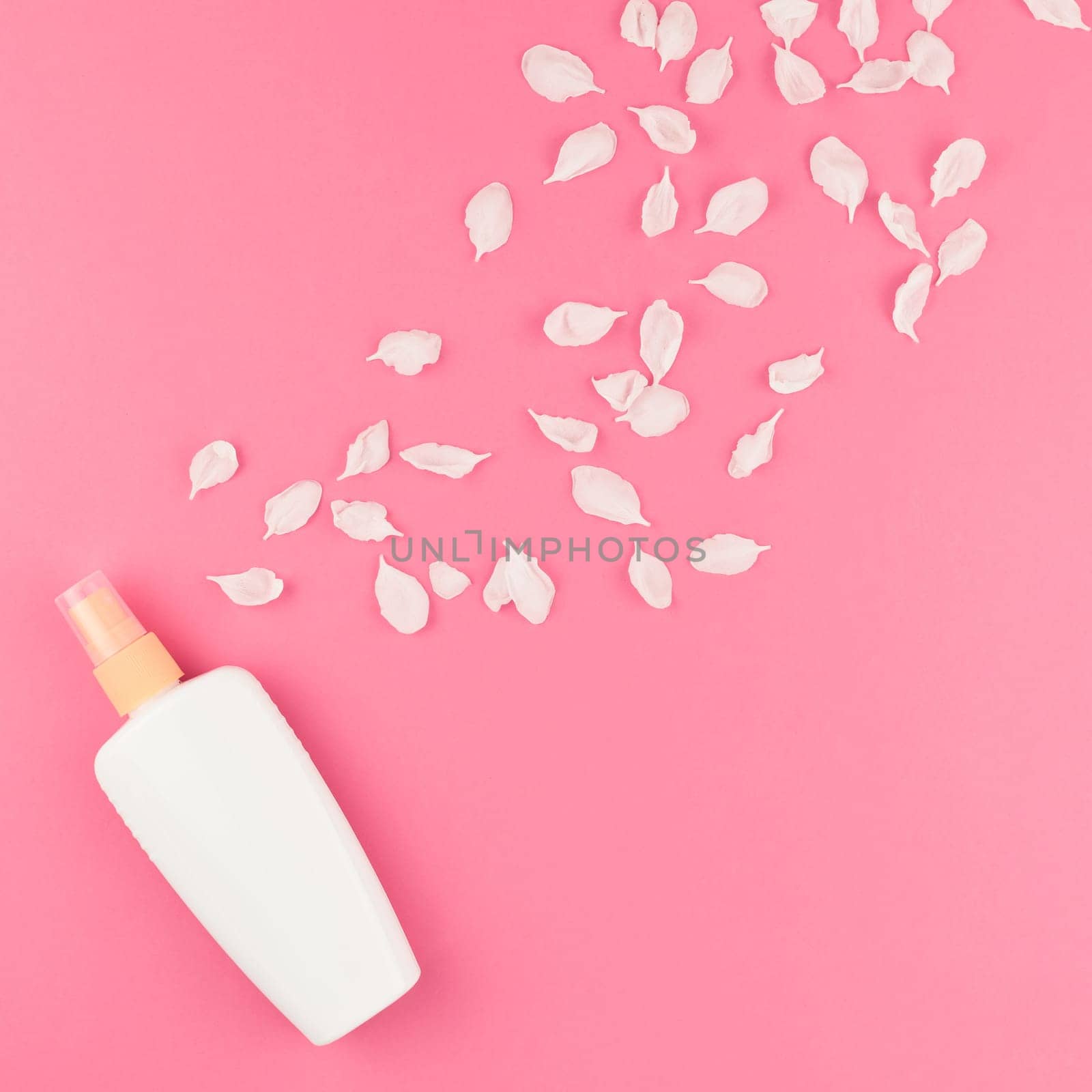 Flat lay set of sunscreen blank bottle mockup and white flowers petals on pastel pink square color background for blog and social media with copy space for text