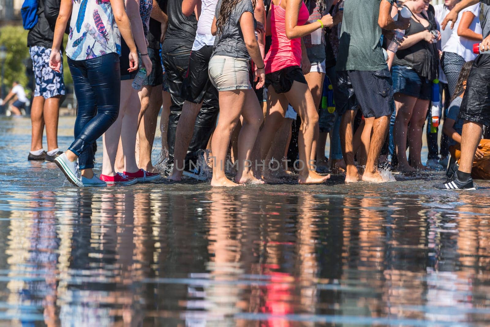 People having fun in a mirror fountain in front of Place de la Bourse in Bordeaux, France