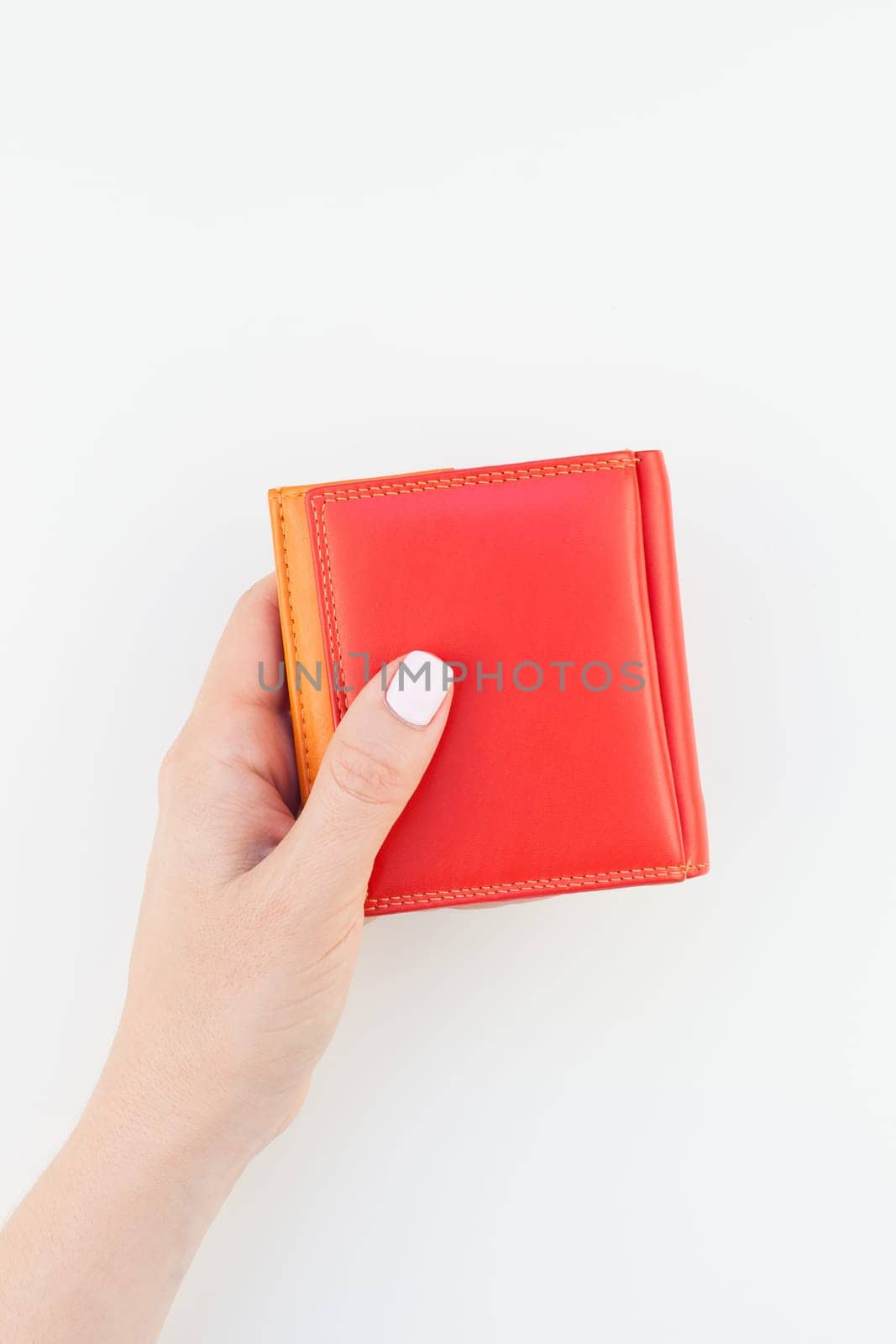 Woman hand with pastel manicure polish holding bright red leather wallet isolated on white background with copy space in minimalism style. Template for feminine beauty blog social financial media
