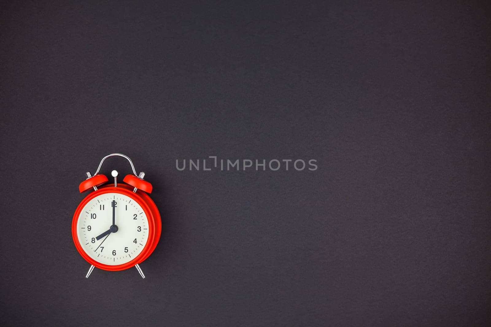 Concept image of a red vintage alarm clock with eight o clock on dark black color paper background with copy space in minimal style, template for text