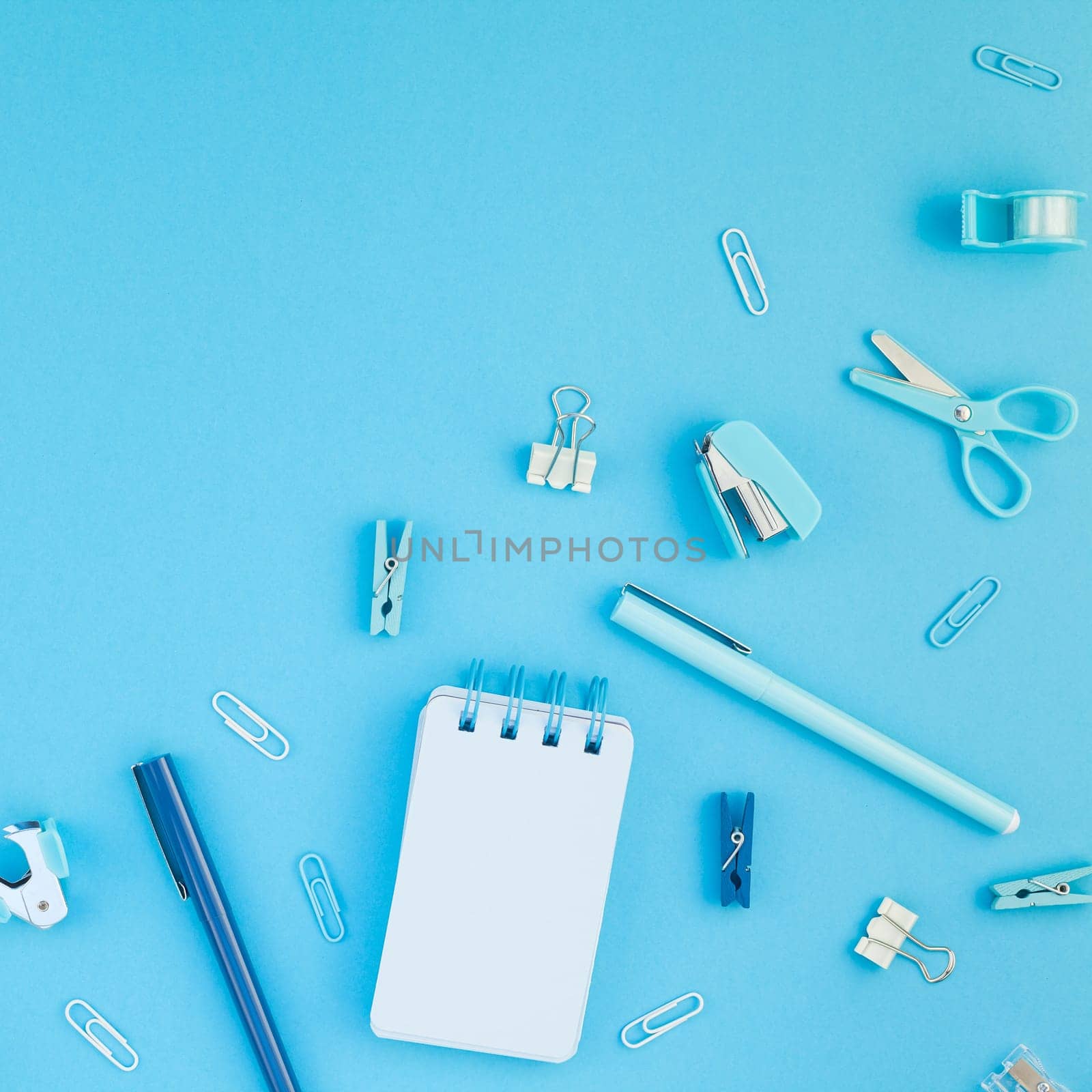 Top view flat lay of workspace desk styled design school and office supplies with copy space turquoise blue color paper background minimal style. Square Template for feminine blog social media