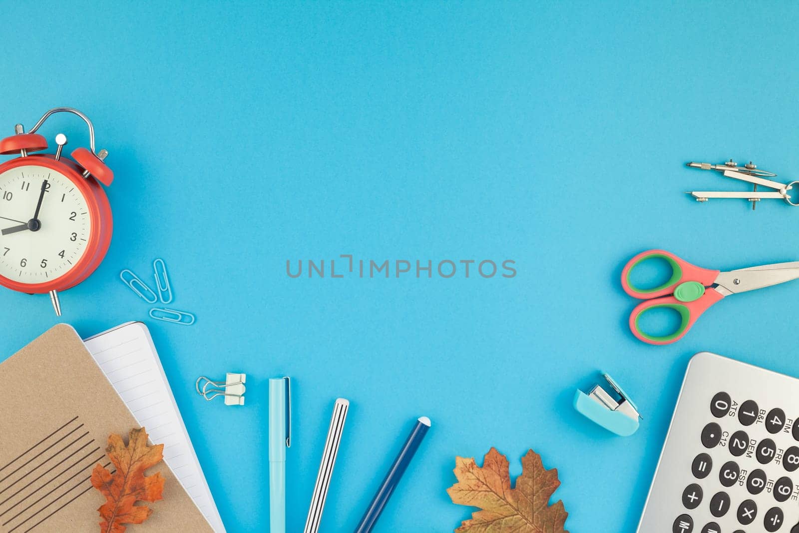 Creative flat lay top view back to school concept with alarm clock, color school and office supplies on bright turquoise paper table frame background with copy space, template for text or design