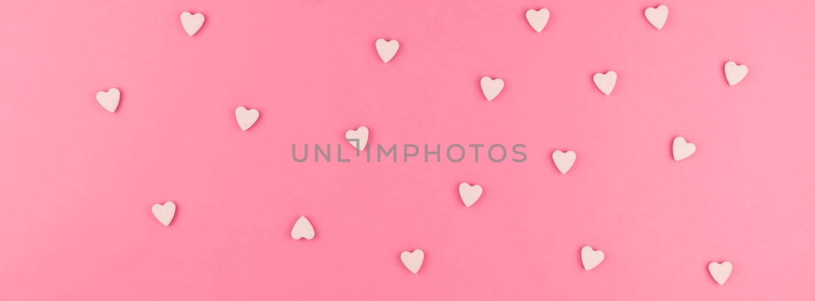 Valentines day pattern background flat lay top view of pink heart shaped candies scattered on pink background love wedding concept. Long wide banner
