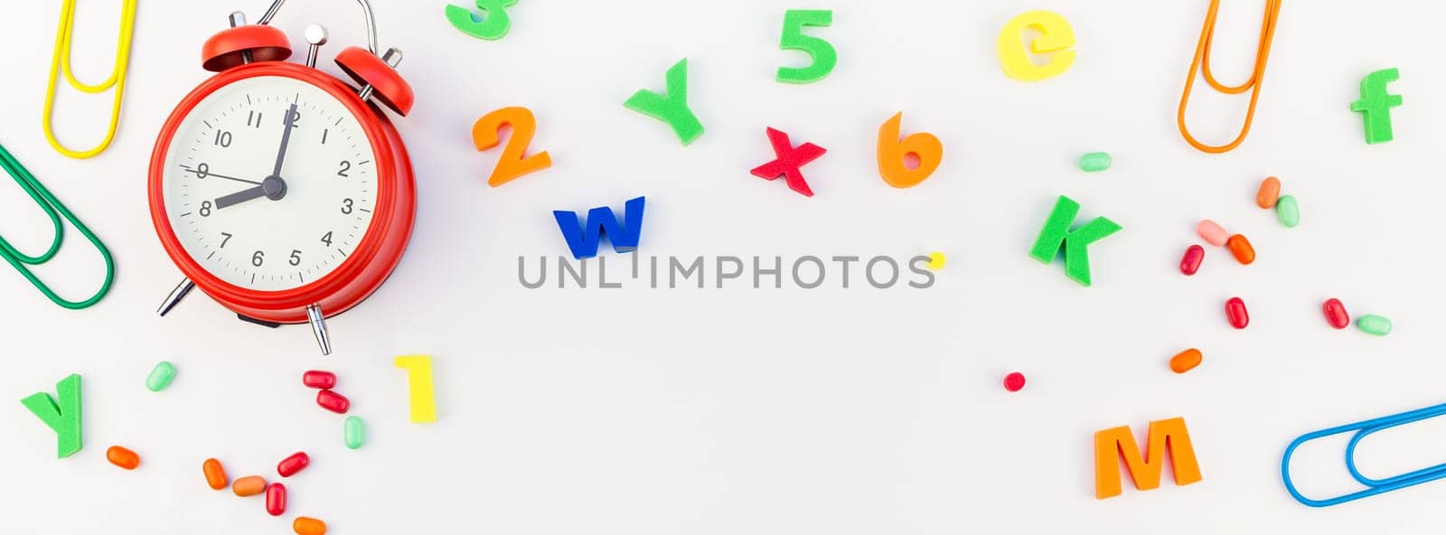 Long wide banner back to school concept with alarm clock, color school and office supplies on white table background with copy space, frame, template for text or design