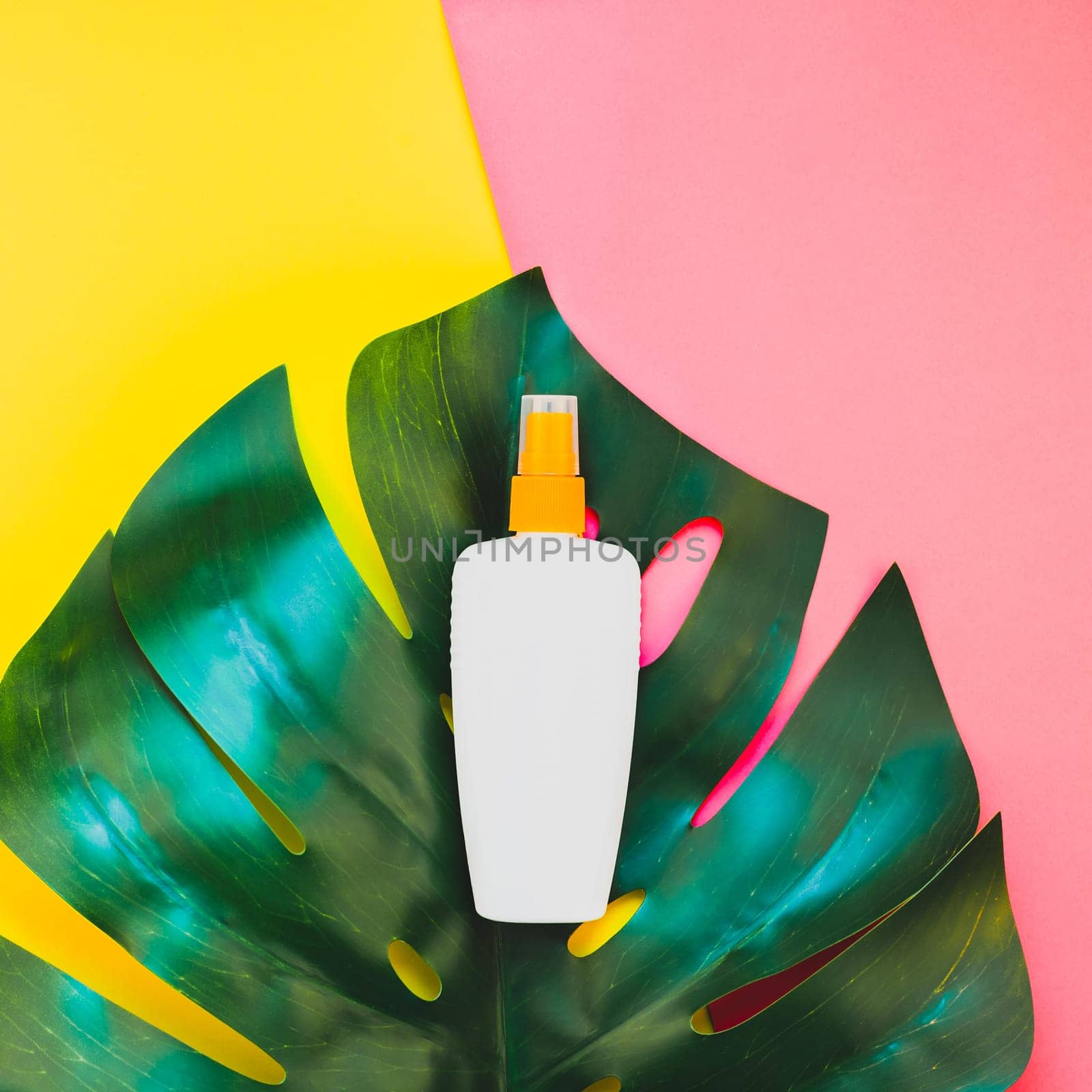 Tropical jungle palm monstera leaves and sunscreen blank bottle mockup on bright square yellow and pink duotone paper background. Summer vacations creative flat lay concept template for text