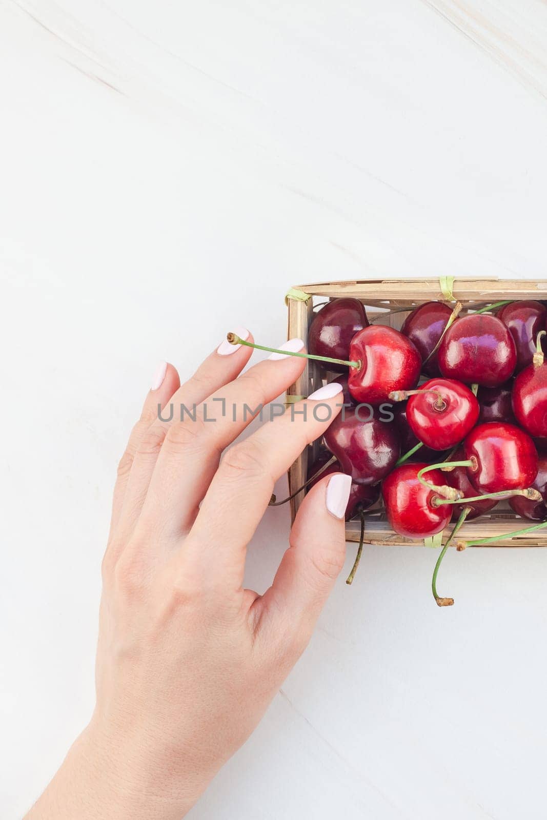 Creative top view of fresh ripe cherry in a small wicker basket with copy space isolated white background minimal style. Concept of summer fun and healthy eating. Template for your text or food design