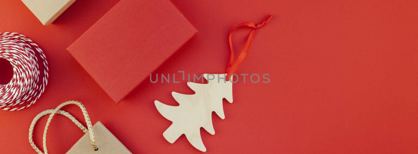 New Year or Christmas presents wrapped with ribbon flat lay top view Xmas 2019 holiday celebration handmade gift boxes on red paper background copyspace. Template mockup long wide banner design