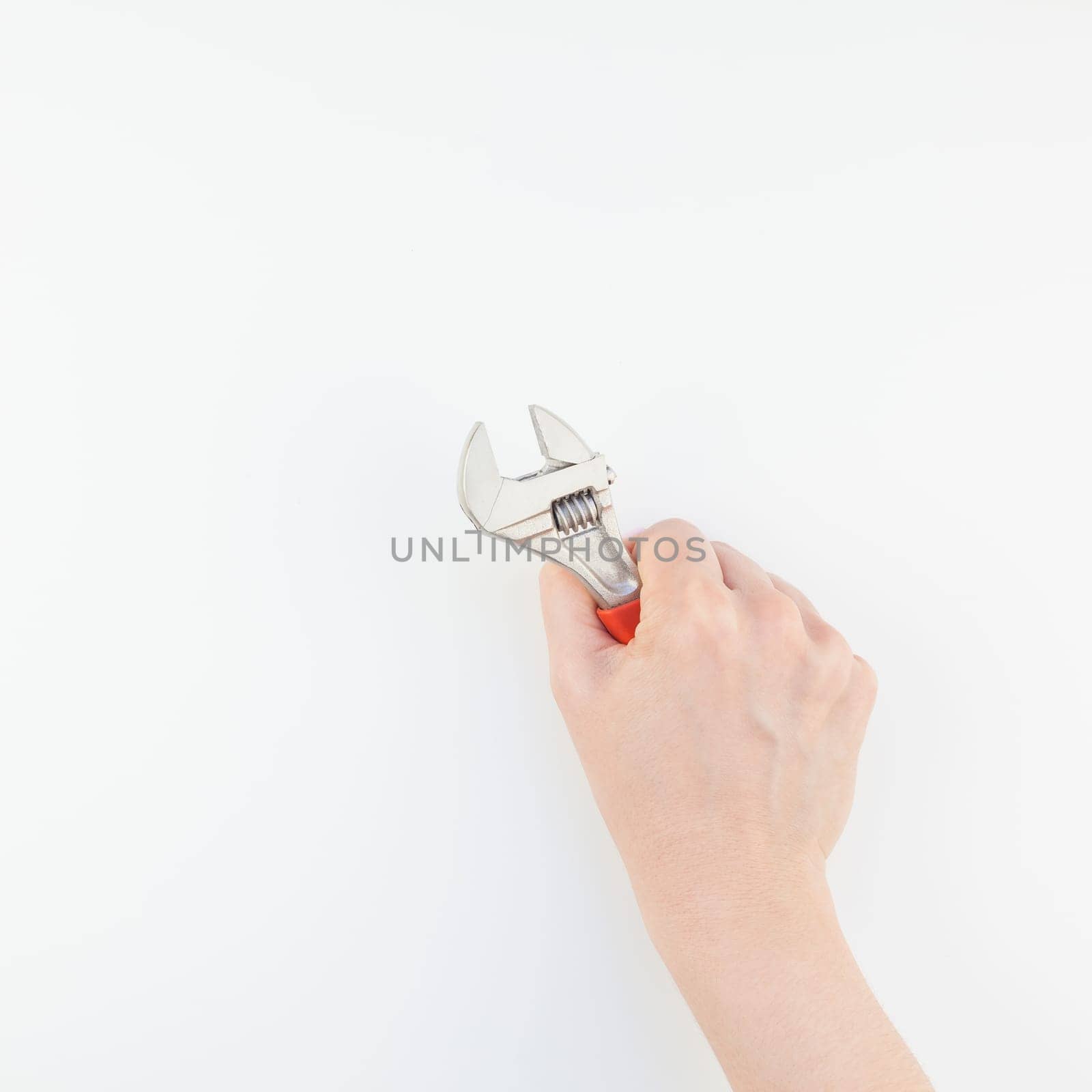 Creative square image of woman hand with pastel manicure polish holding spanner with copy space isolated on white background in minimalism style. Repair or improvement feminism concept