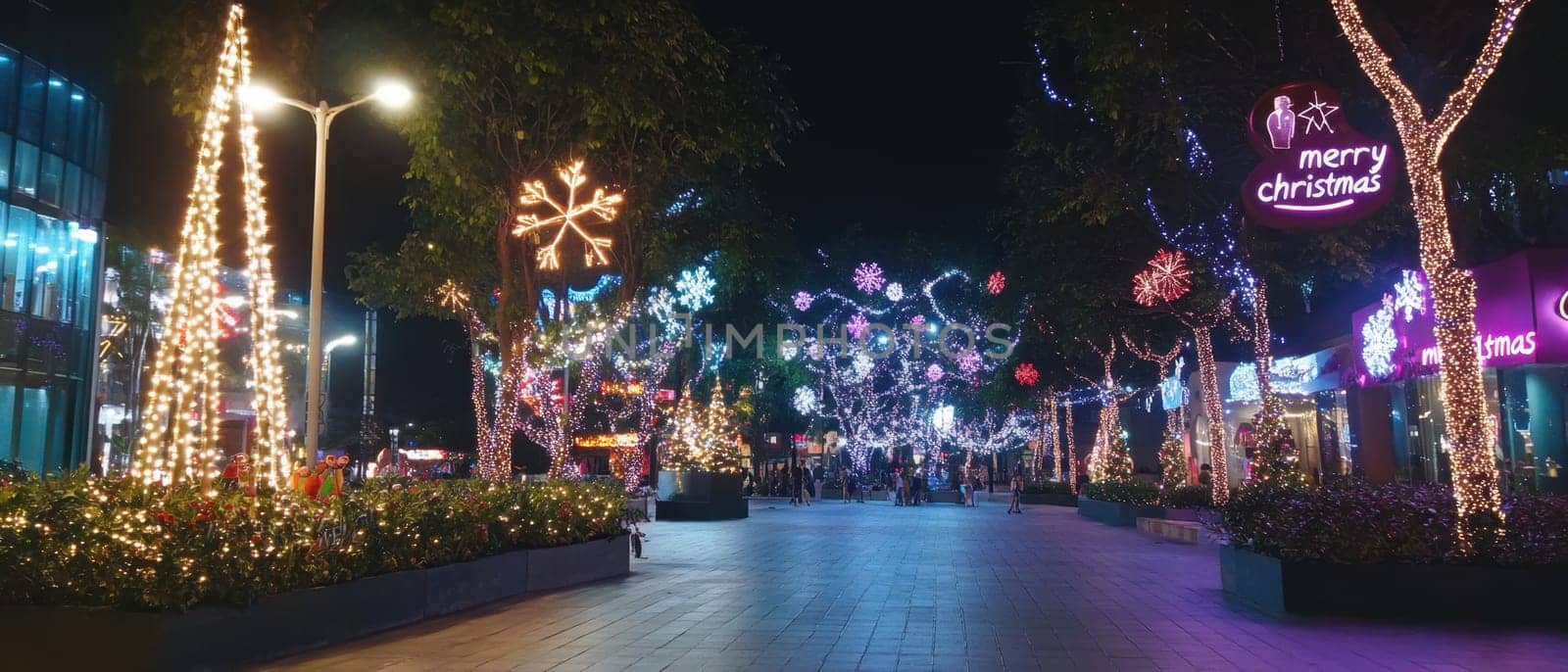 Colorful lights create a cheerful atmosphere along the street celebrating the Christmas season with decorations and lively crowds.