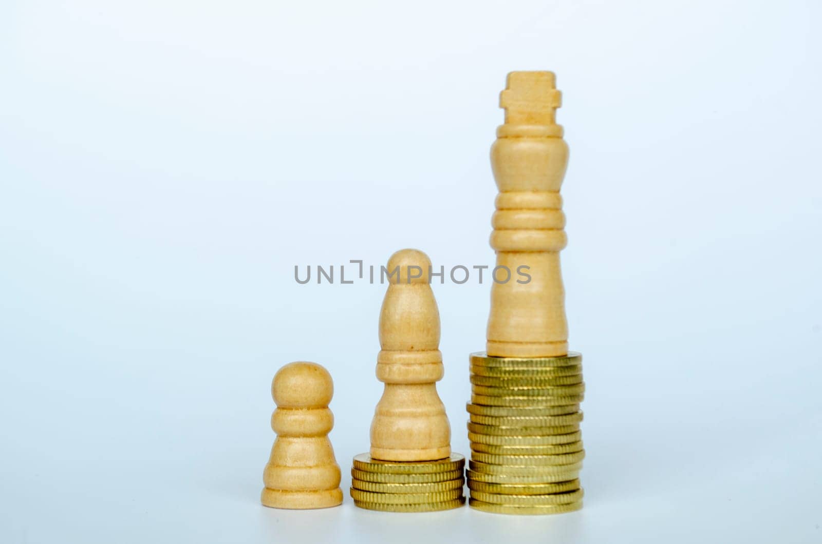 Chess pawns on top of golden stacking coins representing wealth and power.