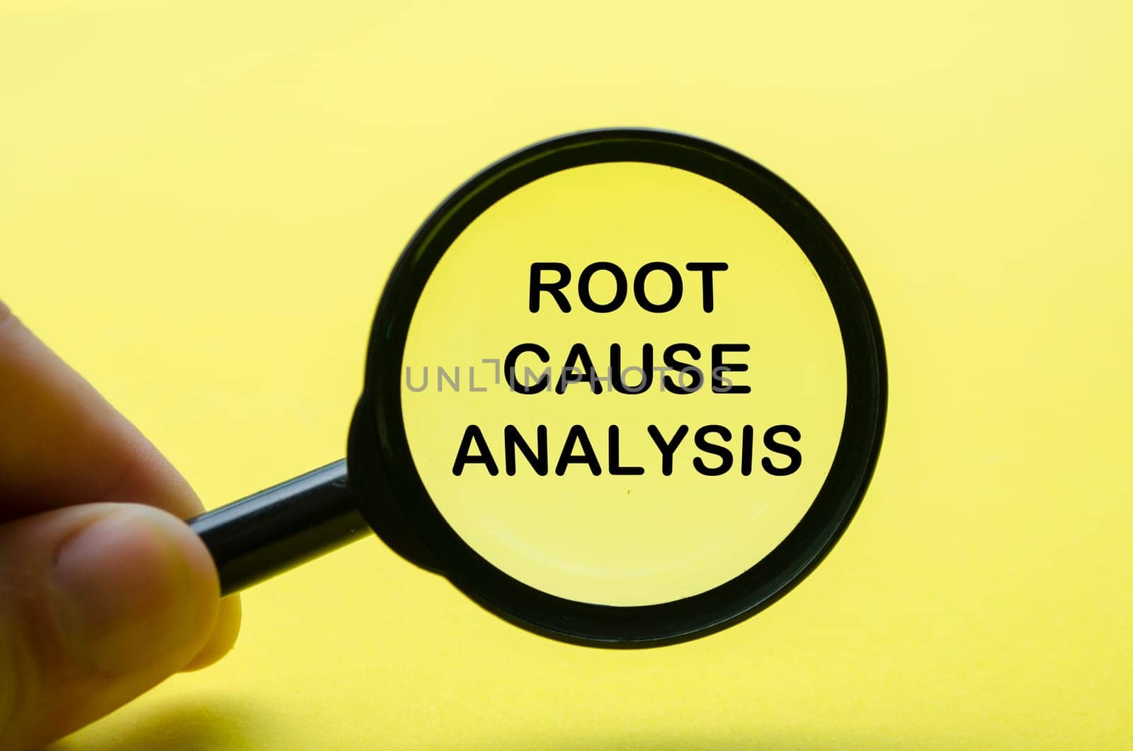 Hand holding magnifying with Root Cause Analysis text on yellow background. Investigation and solution concept.