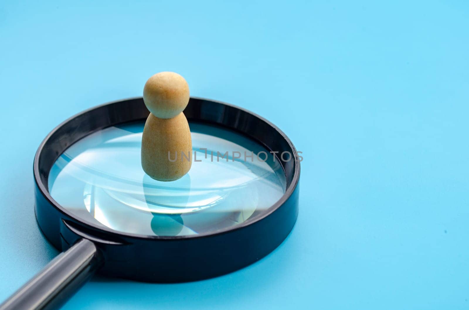 A wooden figure doll standing on top of big magnifying glass with customizable space for text or ideas.