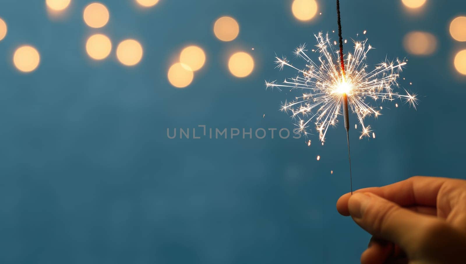 Hand holding a sparkler with bokeh lights. Concept of celebration, holidays, and new beginnings.