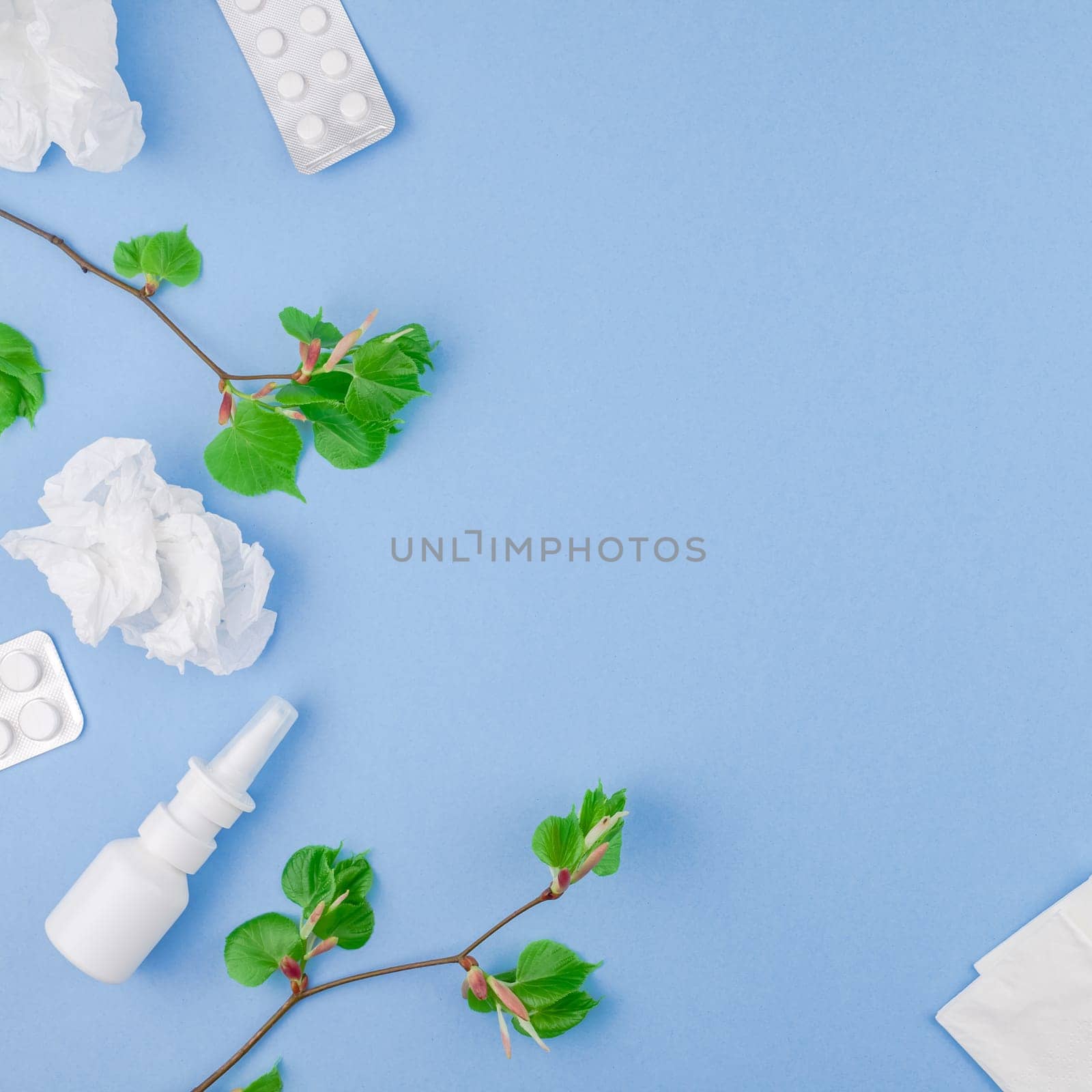 Creative flat lay concept of seasonal spring pollen allergy with napkins, pills, face mask, drops in a bottle and fresh green sprouts with buds. Square copy space background minimal style, template for text