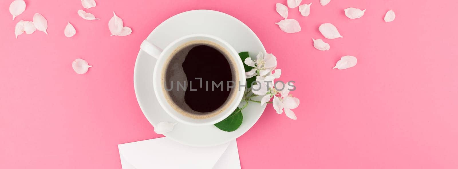 Creative flat lay concept top view of coffee cup and white apple tree flowers petals on pastel pink background with postcard mock up and copy space in minimal style template for text. Long wide banner