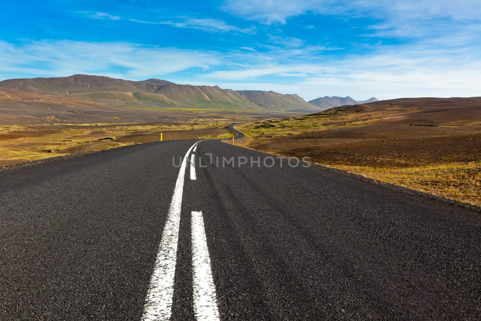 Highway through dry gravel lava field landscape under a blue summer sky. Highlands of Central Iceland.