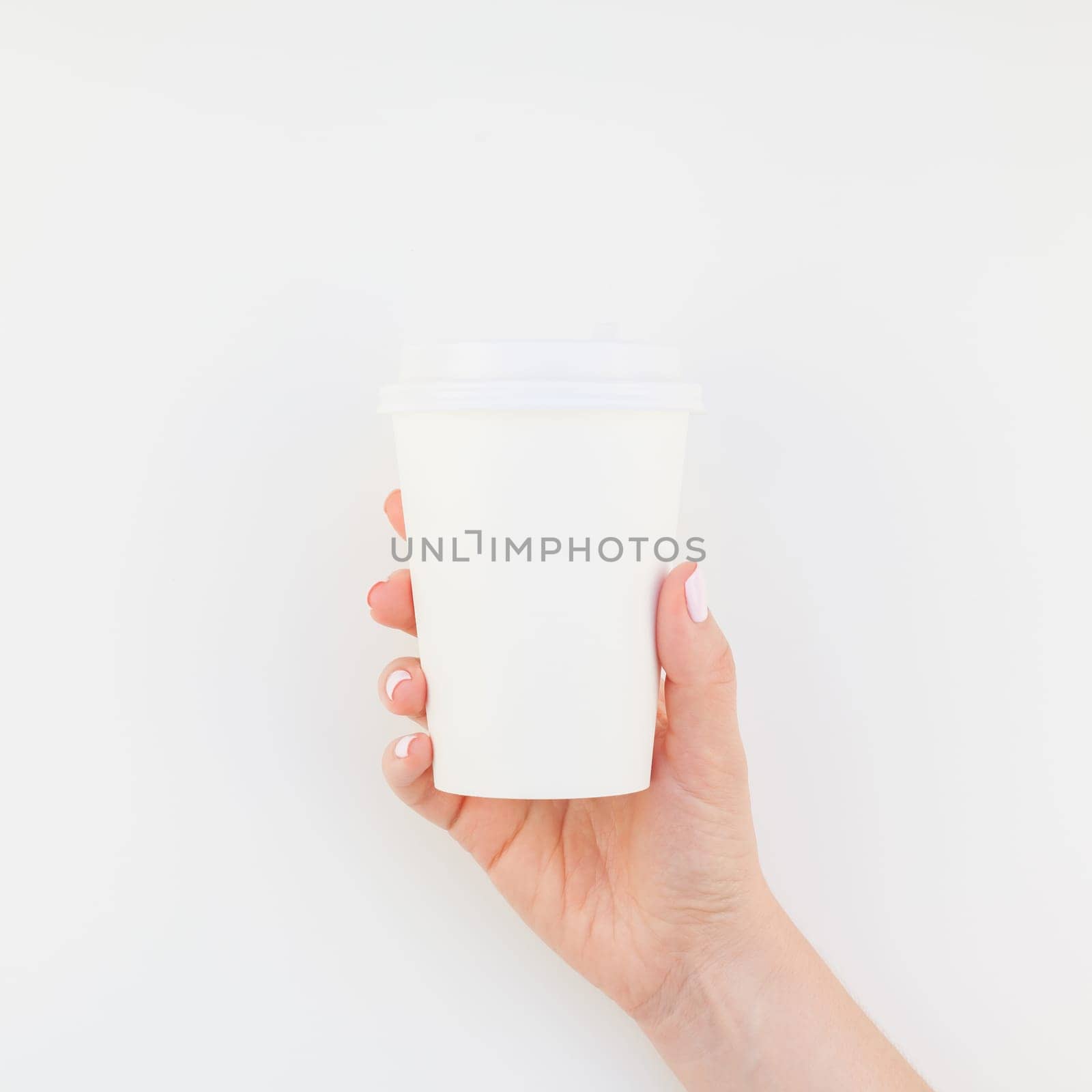 Square mock up image of woman hand holding paper coffee cup with copy space isolated on white background in minimalism style. Template for feminine blog, social media
