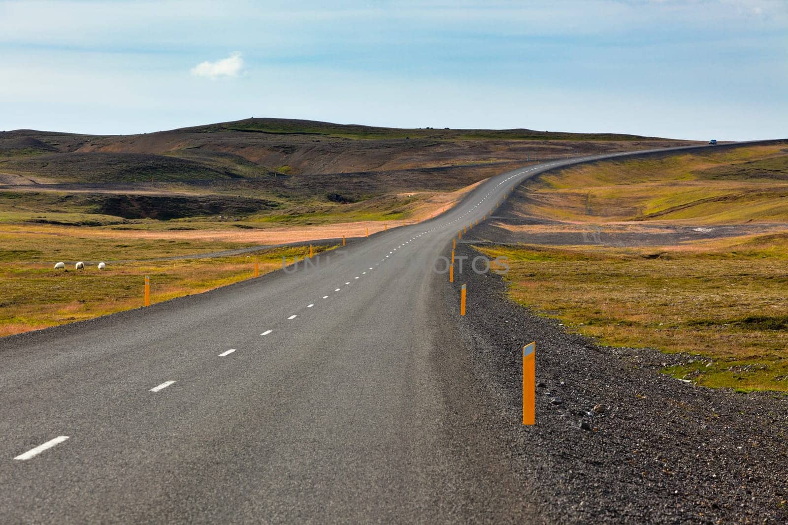 Highway through Icelandic landscape under a blue summer sky with clouds