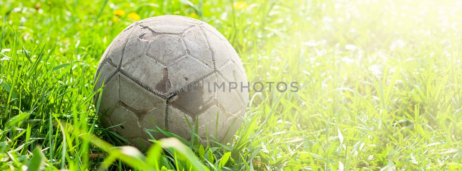 Old soccer ball forgotten in the green grass field. The football concept. Long wide banner