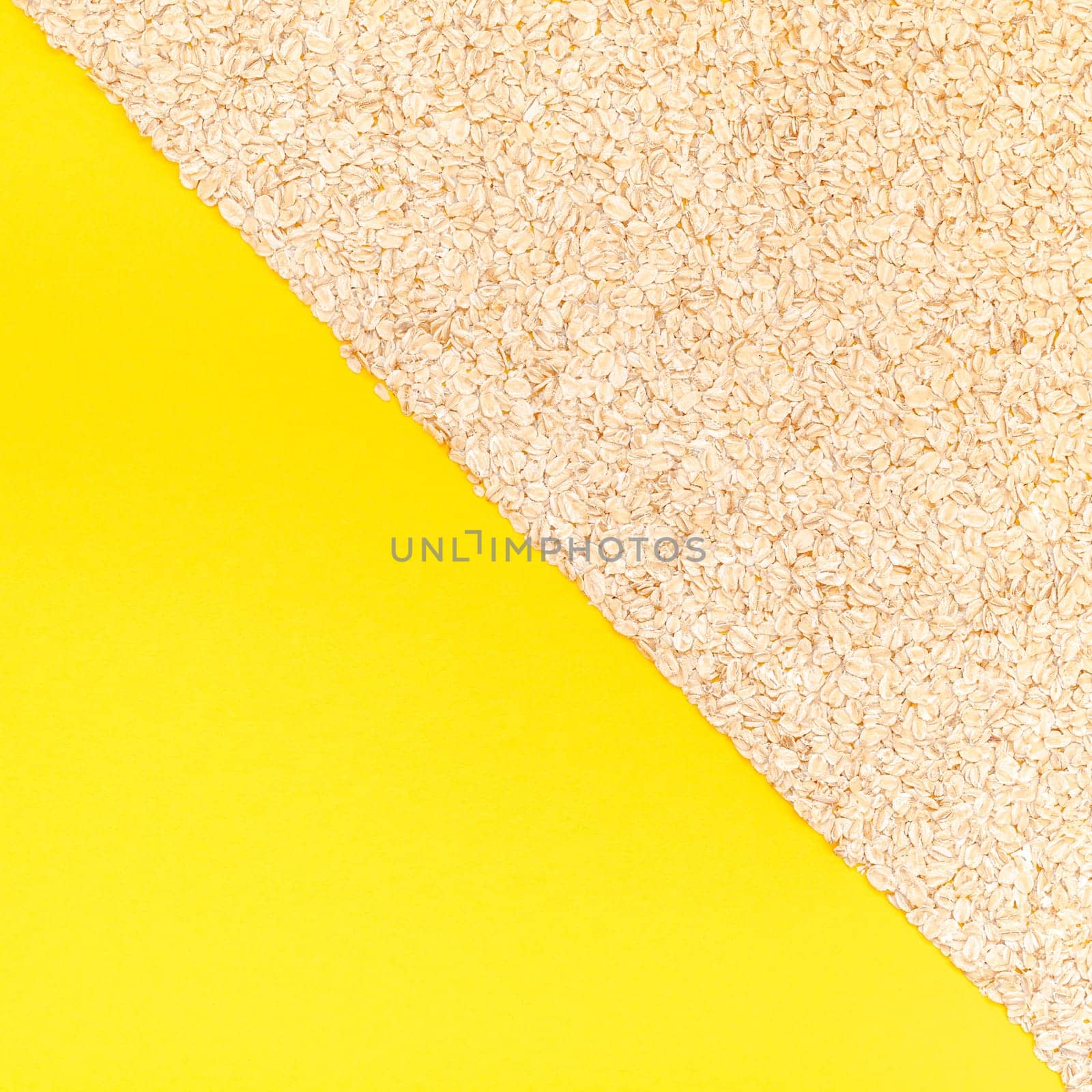 Creative flat lay concept top view of oatmeal flakes for healthy and vegetarian organic food for breakfast on a bright yellow color paper background with copy space in minimal style, square template