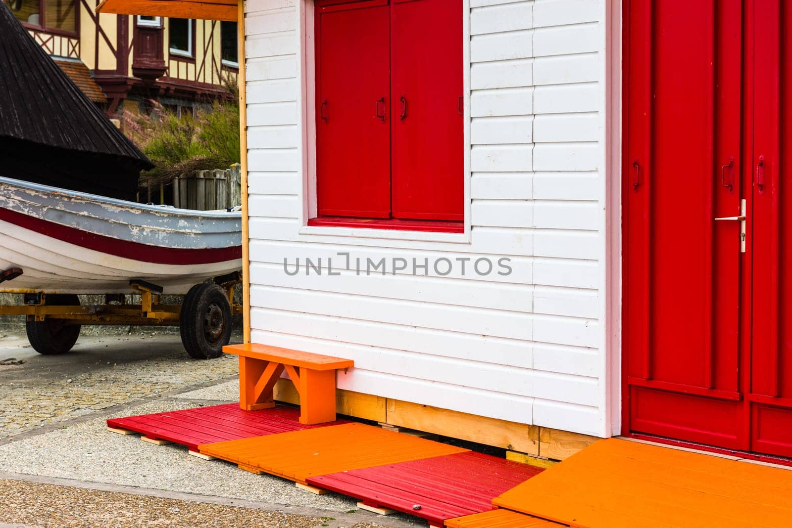 Fishing boat near white wooden country house with a red door and window