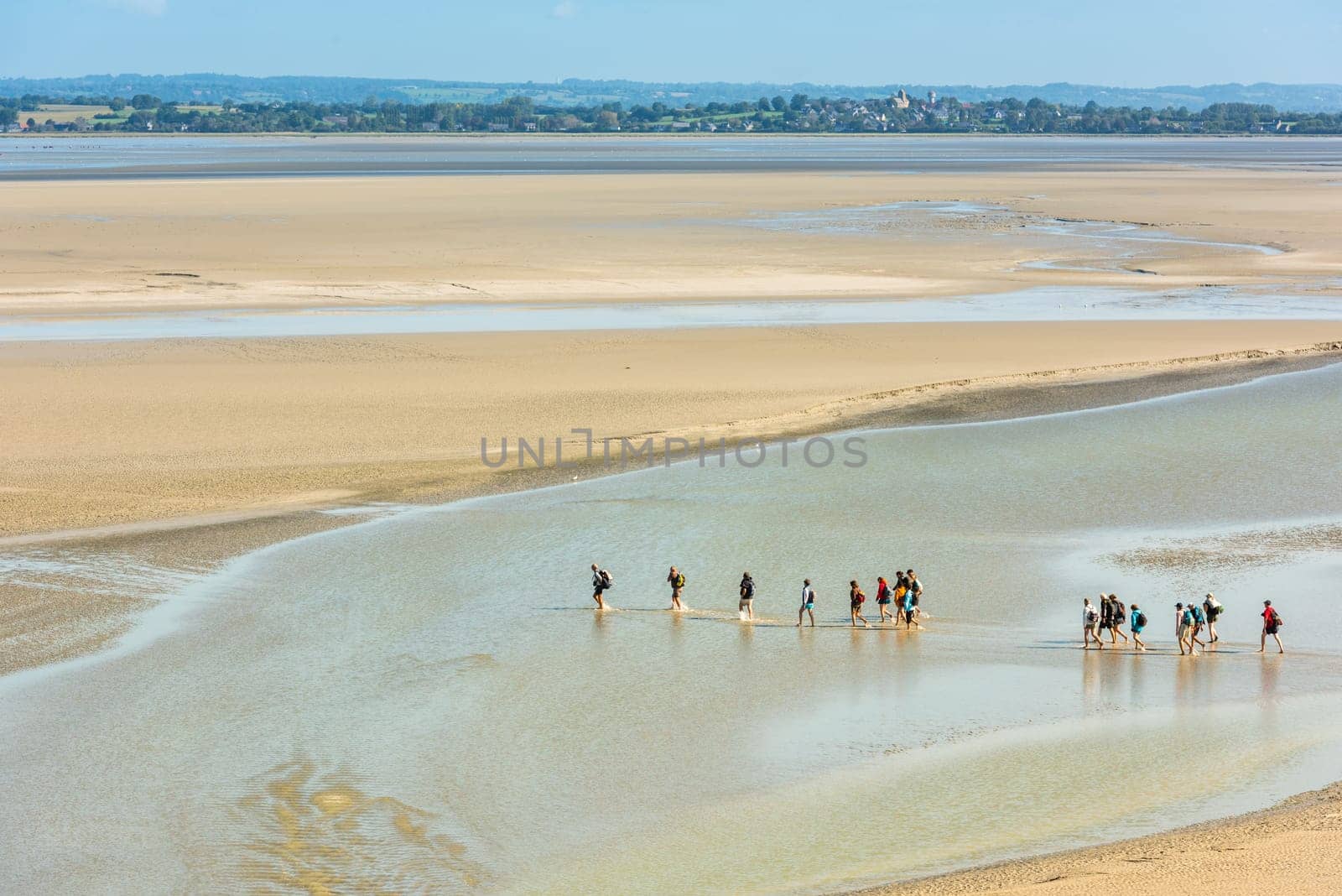 FRANCE, MONT SAINT MICHEL - SEPTEMBER 26: View from walls of Mont Saint Michel on the bay during the low tide with groups of tourists walking. France on September 26, 2015