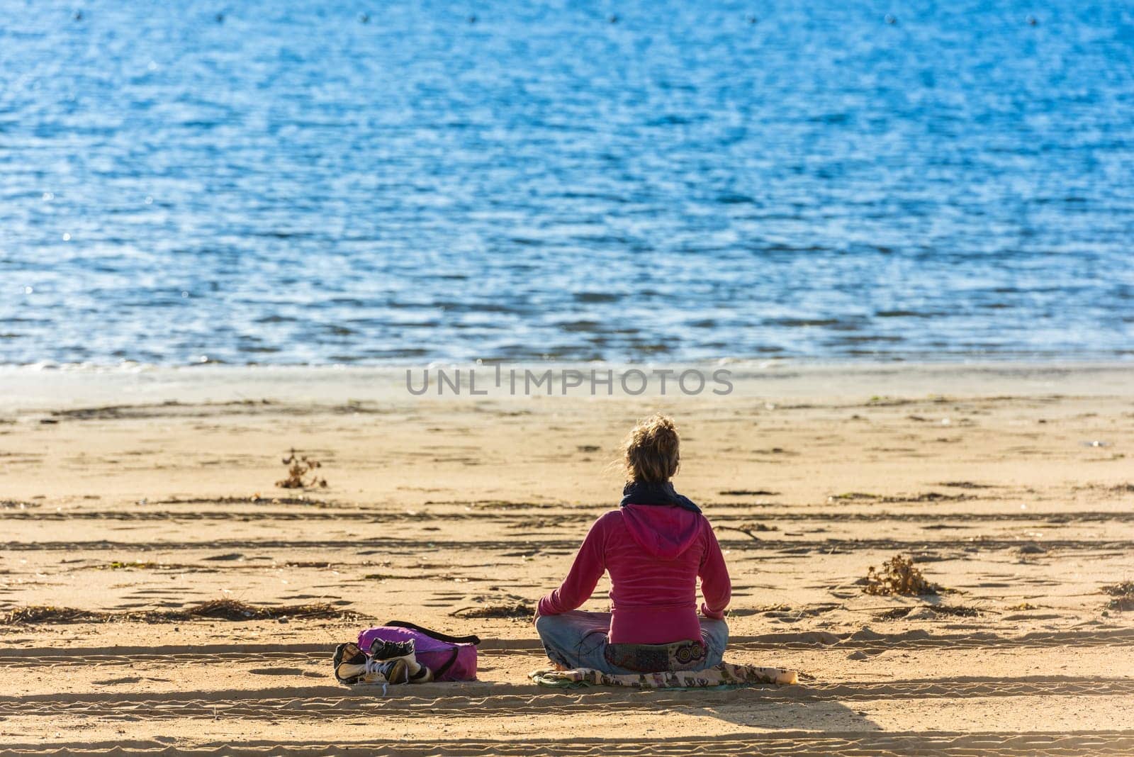 FRANCE, ARCACHON - SEPTEMBER 18: girl is sitting on the sand beach and looking at the blue water on September 18, 2015