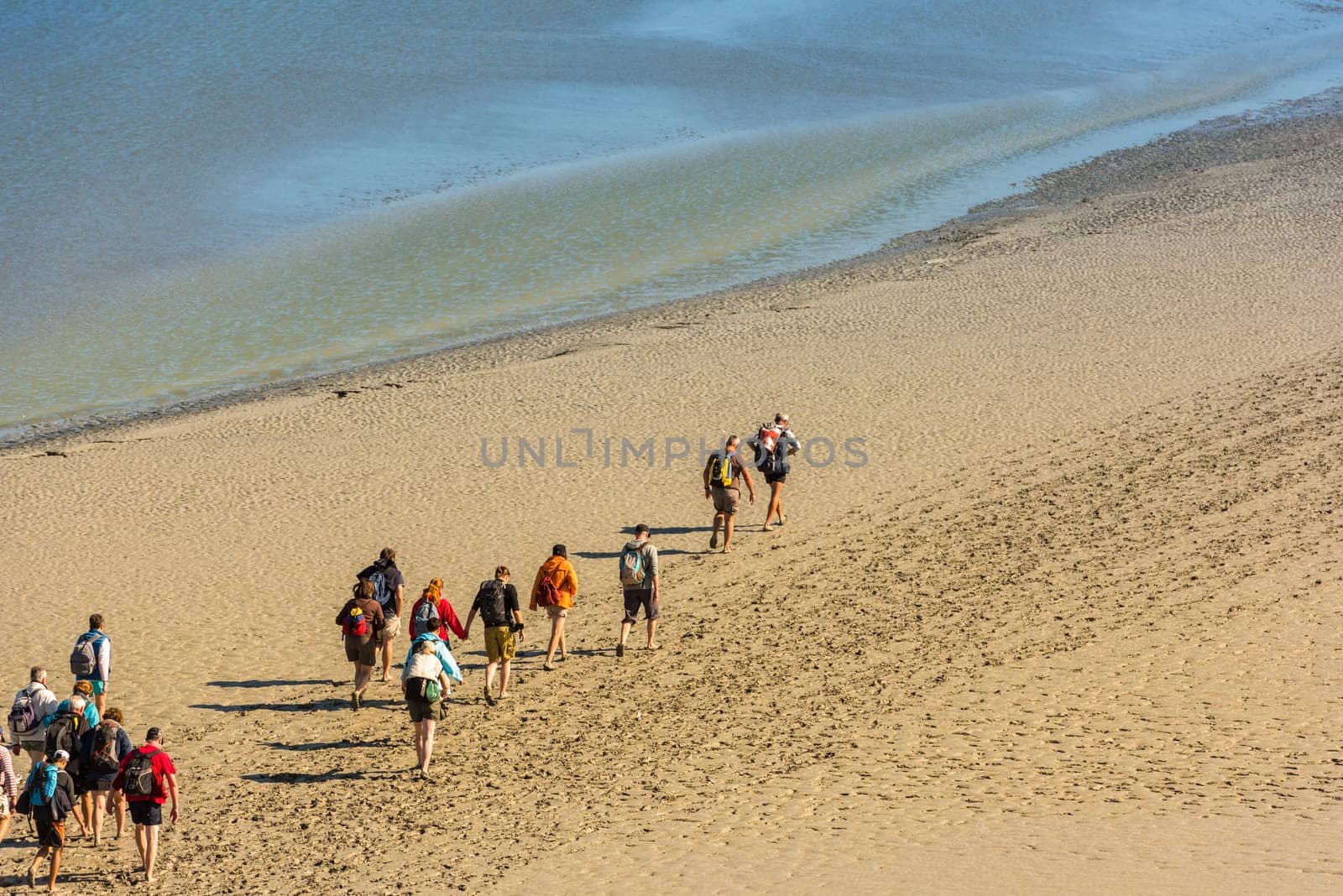 FRANCE, MONT SAINT MICHEL - SEPTEMBER 26: View from walls of Mont Saint Michel on the bay during the low tide with groups of tourists walking. France on September 26, 2015