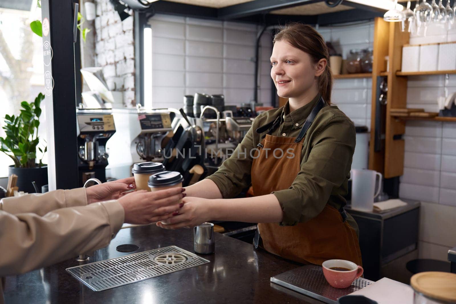 Female barista serving coffee in takeaway recycling paper cups. Female client receiving order at coffee-shop