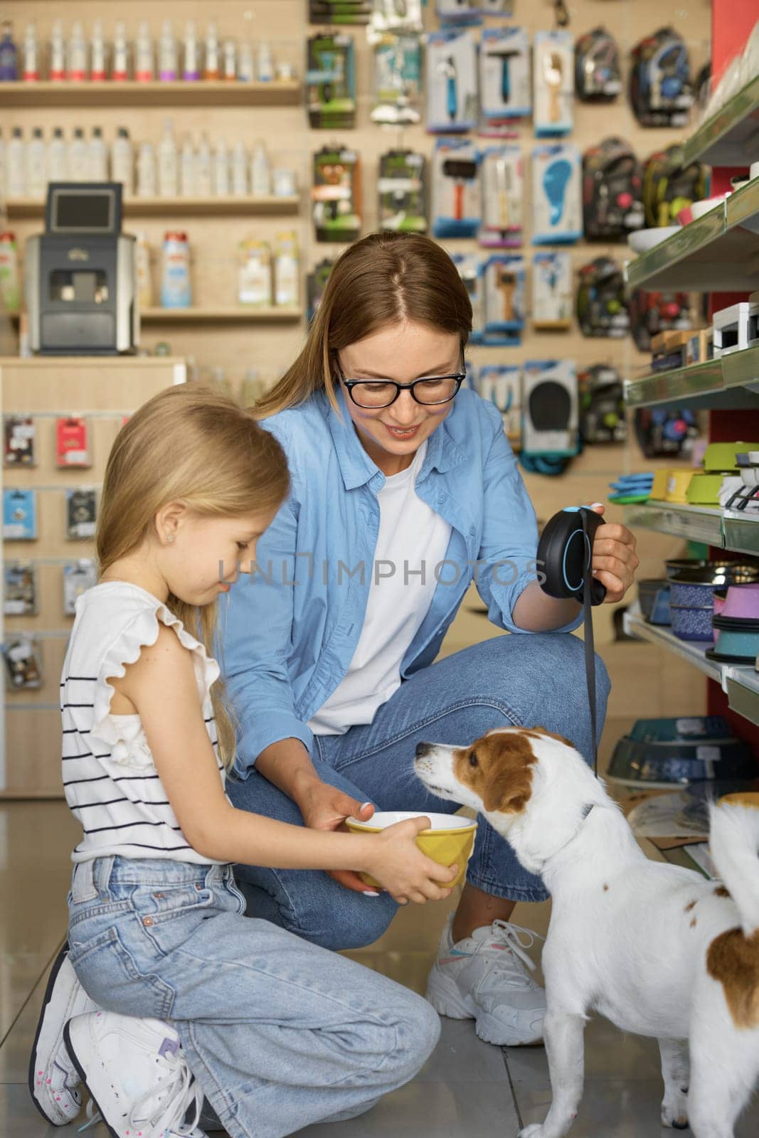 Family in pet store. Mother and her daughter choosing new food bowl for their dog. Labrador dog enjoying shopping at pet store