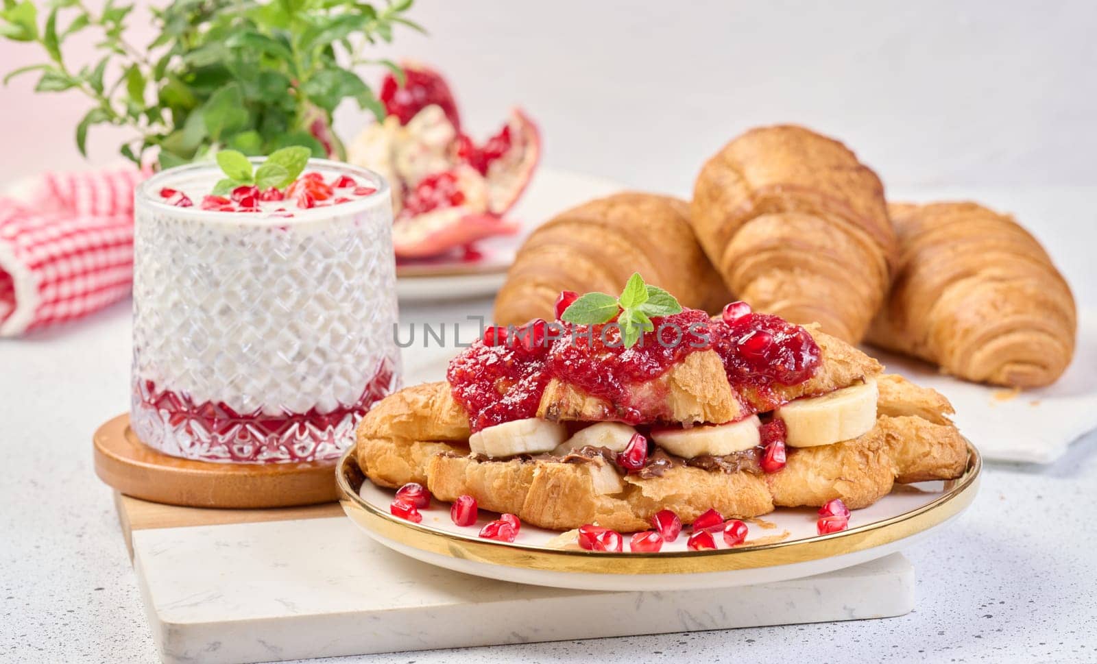 Croissant with chocolate, banana pieces and raspberry jam on a plate