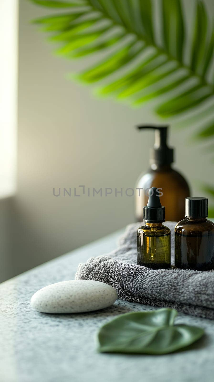 Natural spa setting with amber bottles, gray towel, white stone and tropical palm leaf, aromatherapy oils for wellness treatment, copy space.