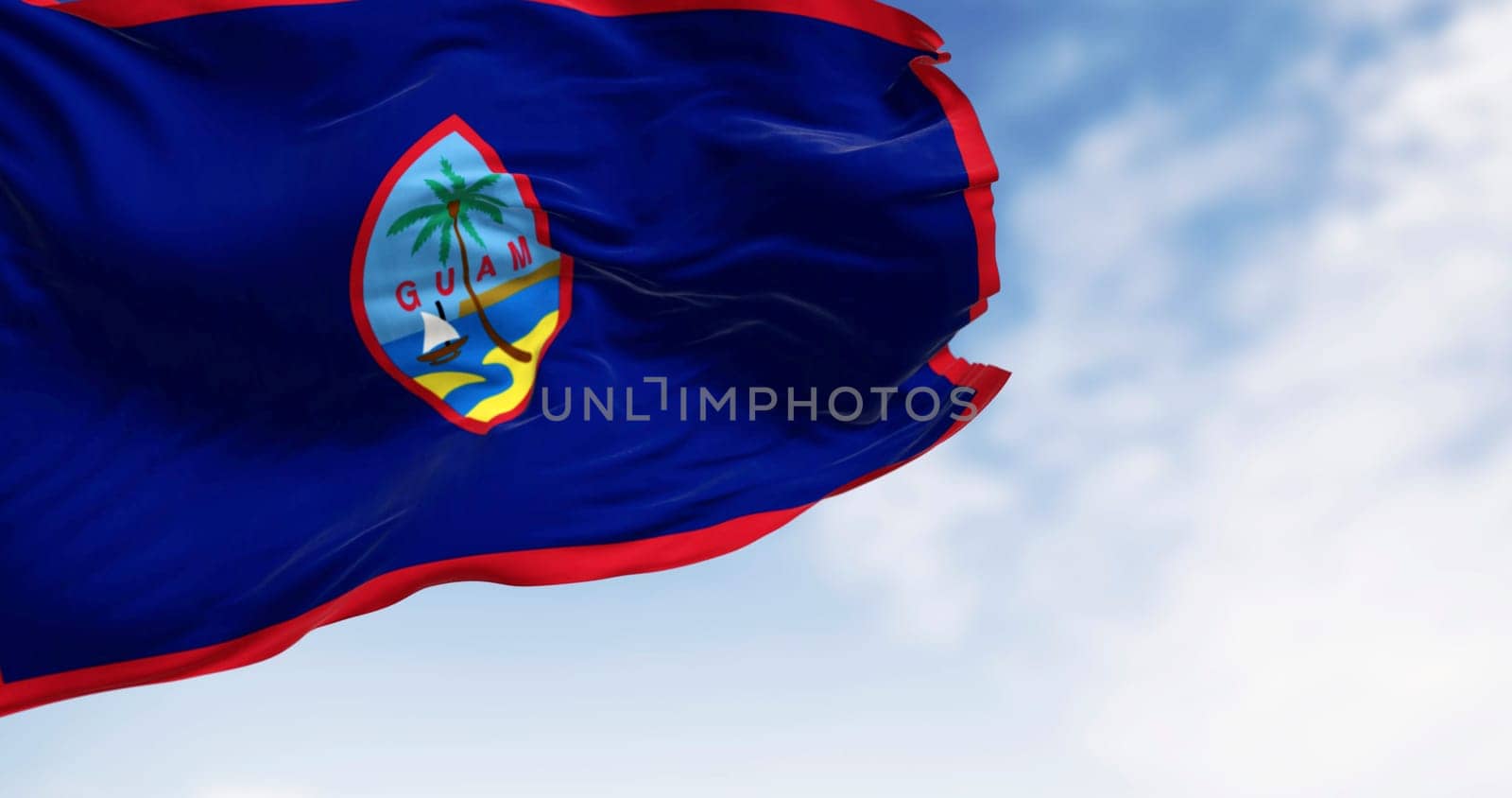 Guam national flag waving in the wind on a clear day. Unincorporated territory of the U.S. in the Micronesia subregion of the western Pacific Ocean. 3d illustration render. Waving fabric