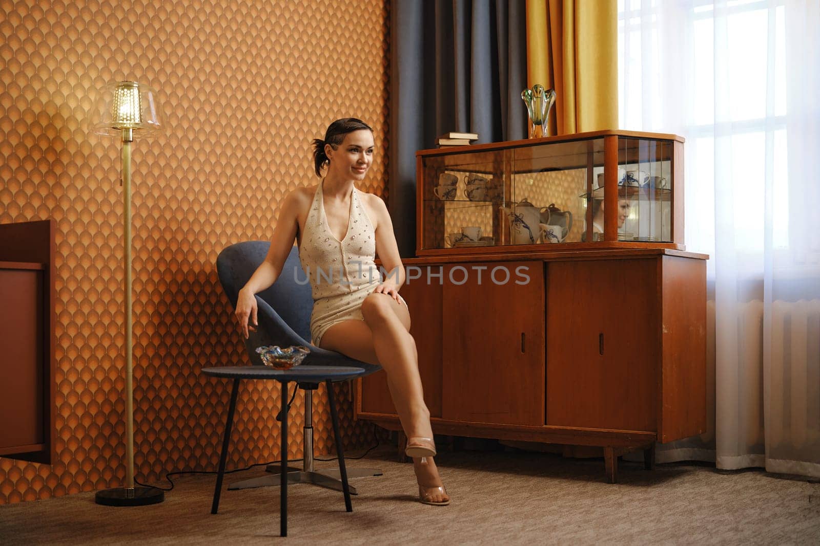 Elegant woman in vintage body suit sits in old-fashioned living room
