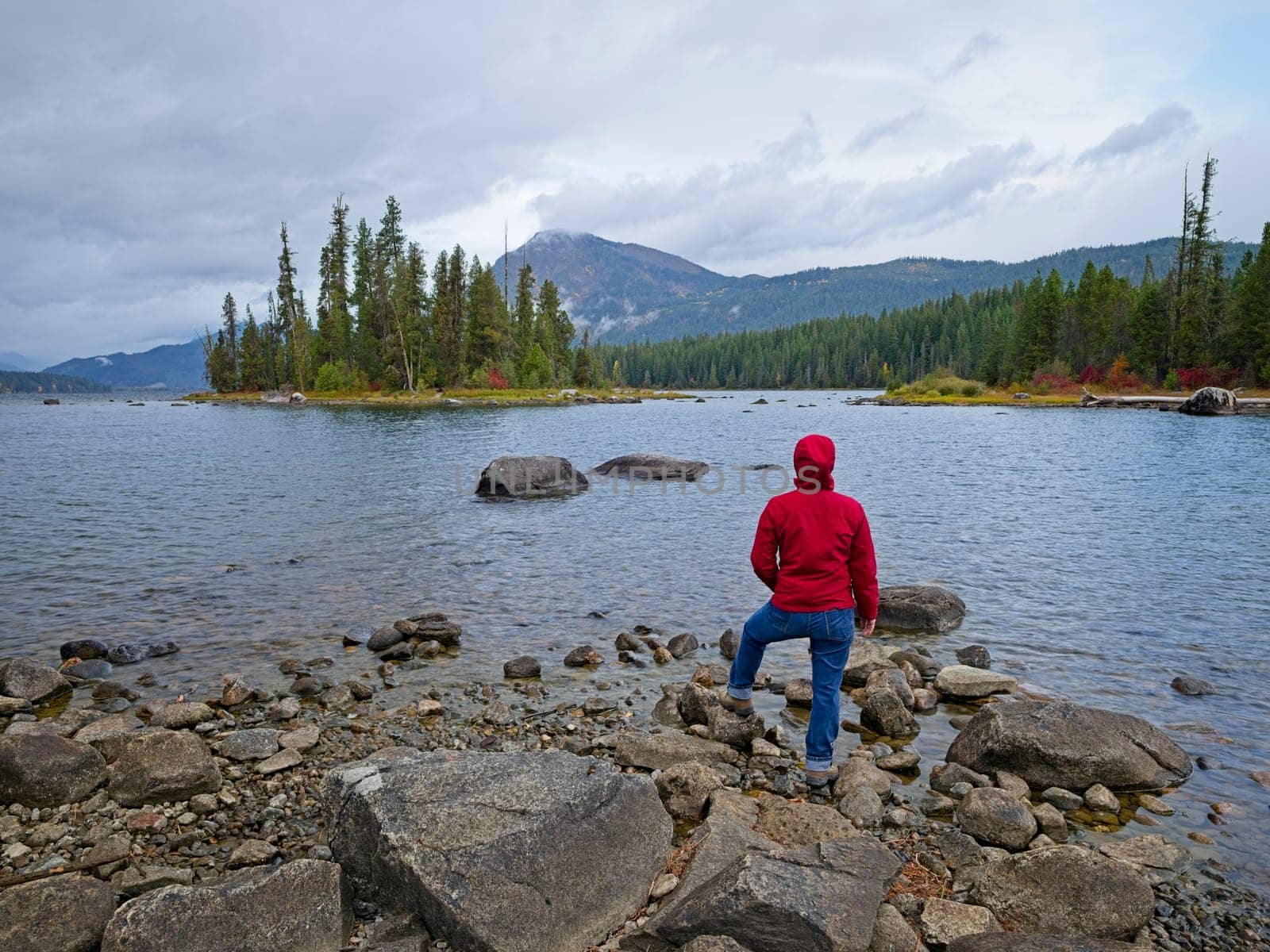 A woman stands by the rocky shore of Lake Wenatchee on a cloudy morning in central Washington.