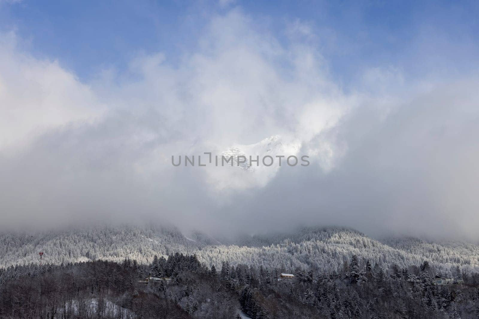 Beautiful view of the snow peaks of the Alps mountains above the city, clouds against the blue sky, Innsbruck, Austria