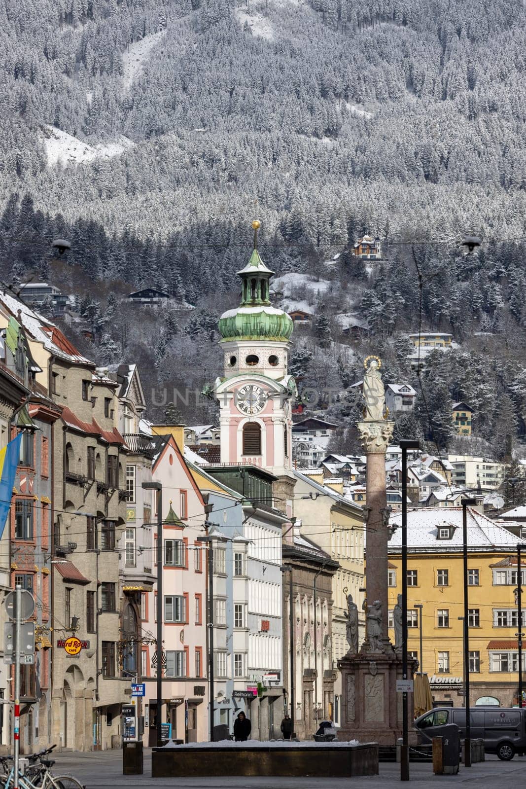 Innsbruck, Austria - August 4, 2022: View of the Alte Spitalskirche (Hospital Church of the Holy Spirit) bell tower and Column of St. Anna on Maria Theresa Street