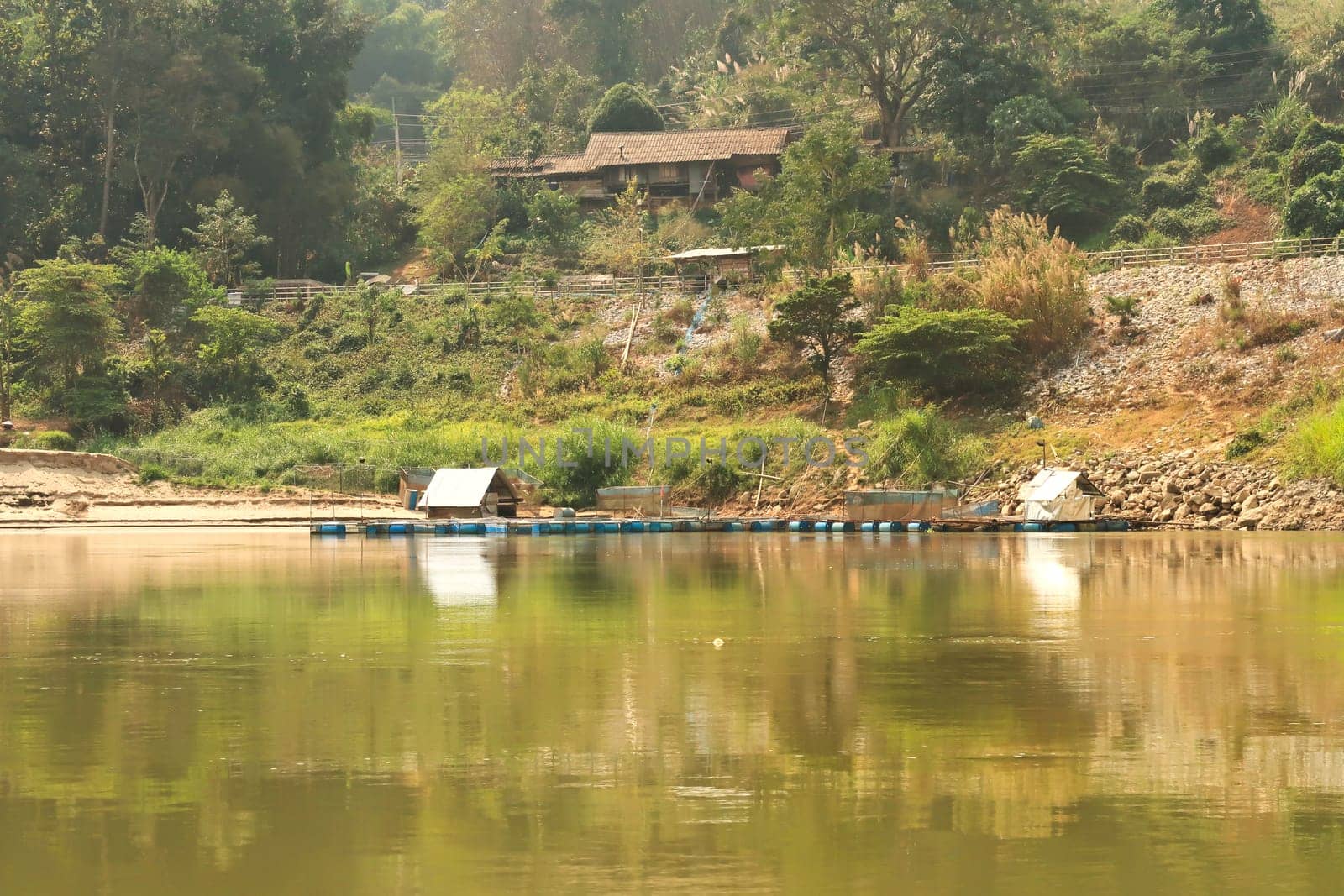 View from the slow boat from Thailand to Laos onto the shore of the Mekong River with a aquaculture installation, Laos 2023