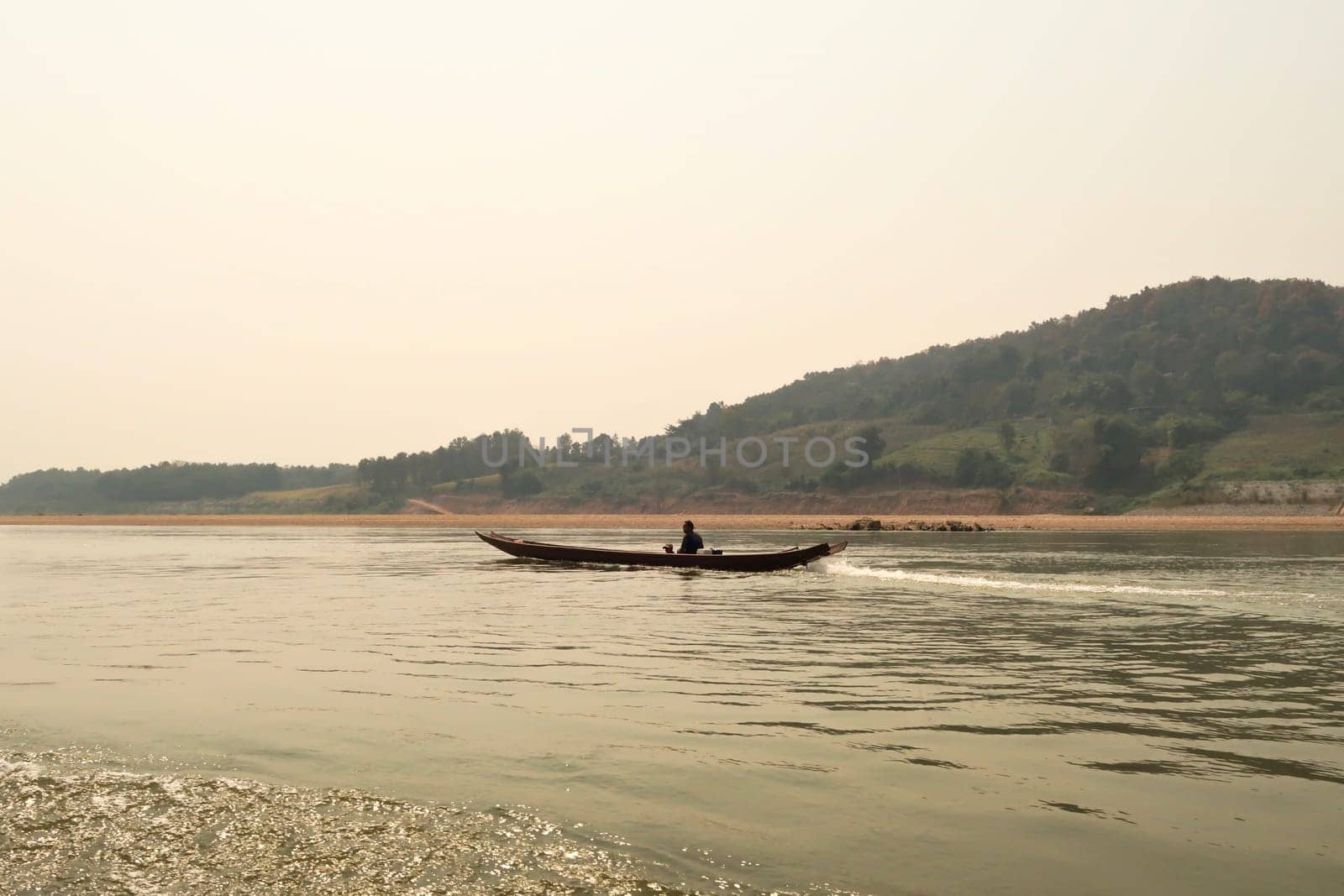 View from the slow boat from Thailand to Laos onto a small boat with two locals on the Mekong River, Laos 2023