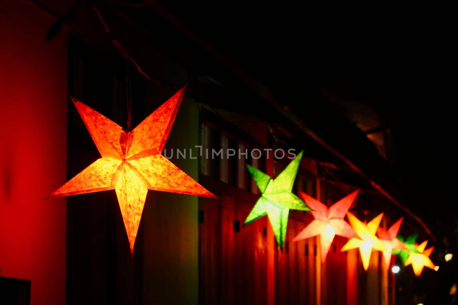 Many colorful star shaped lanterns illuminate a street in the old town of Luang Prabang at night, Laos 2023