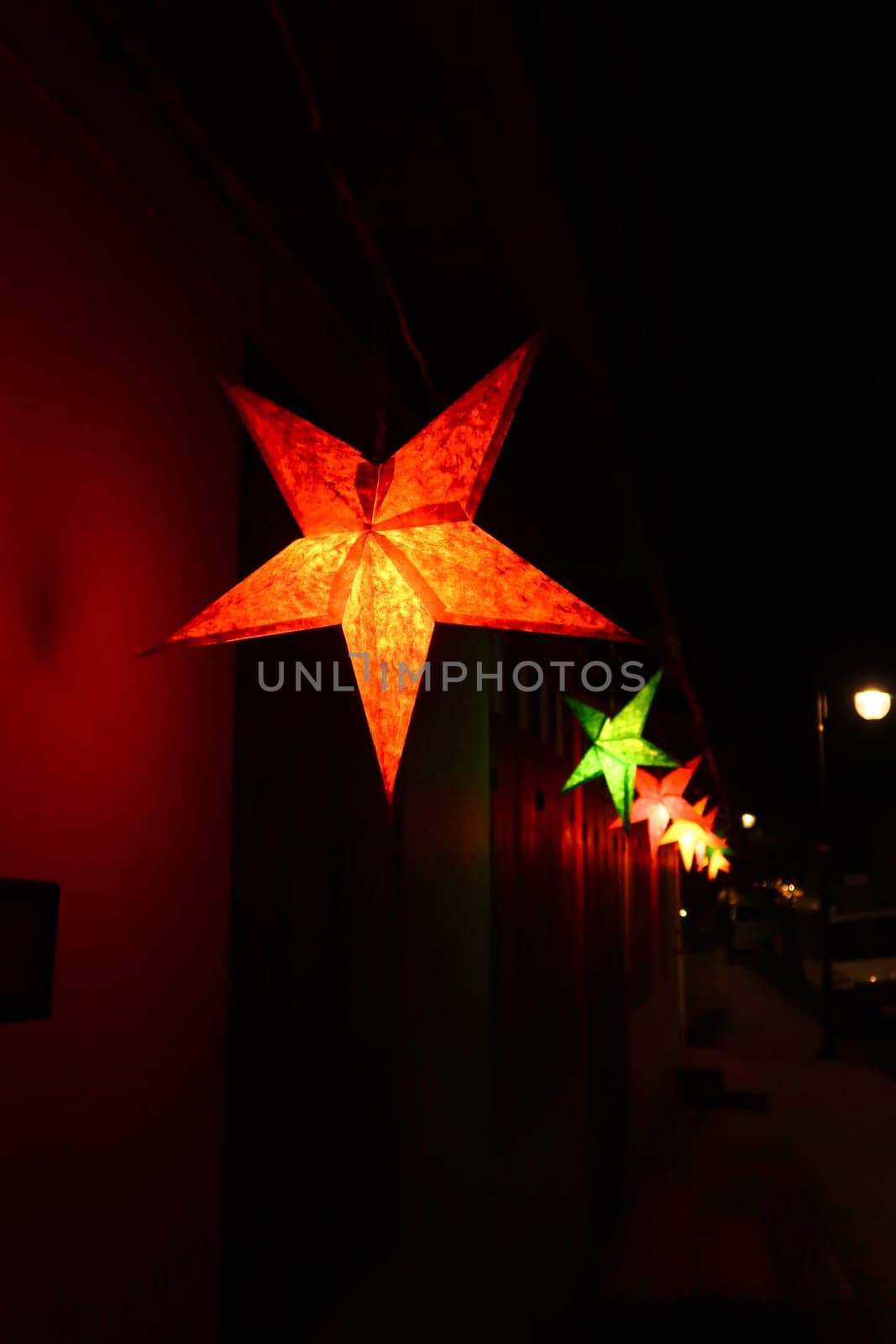 A row of colorful star shaped lanterns illuminating the night in the old town of Luang Prabang, Laos 2023