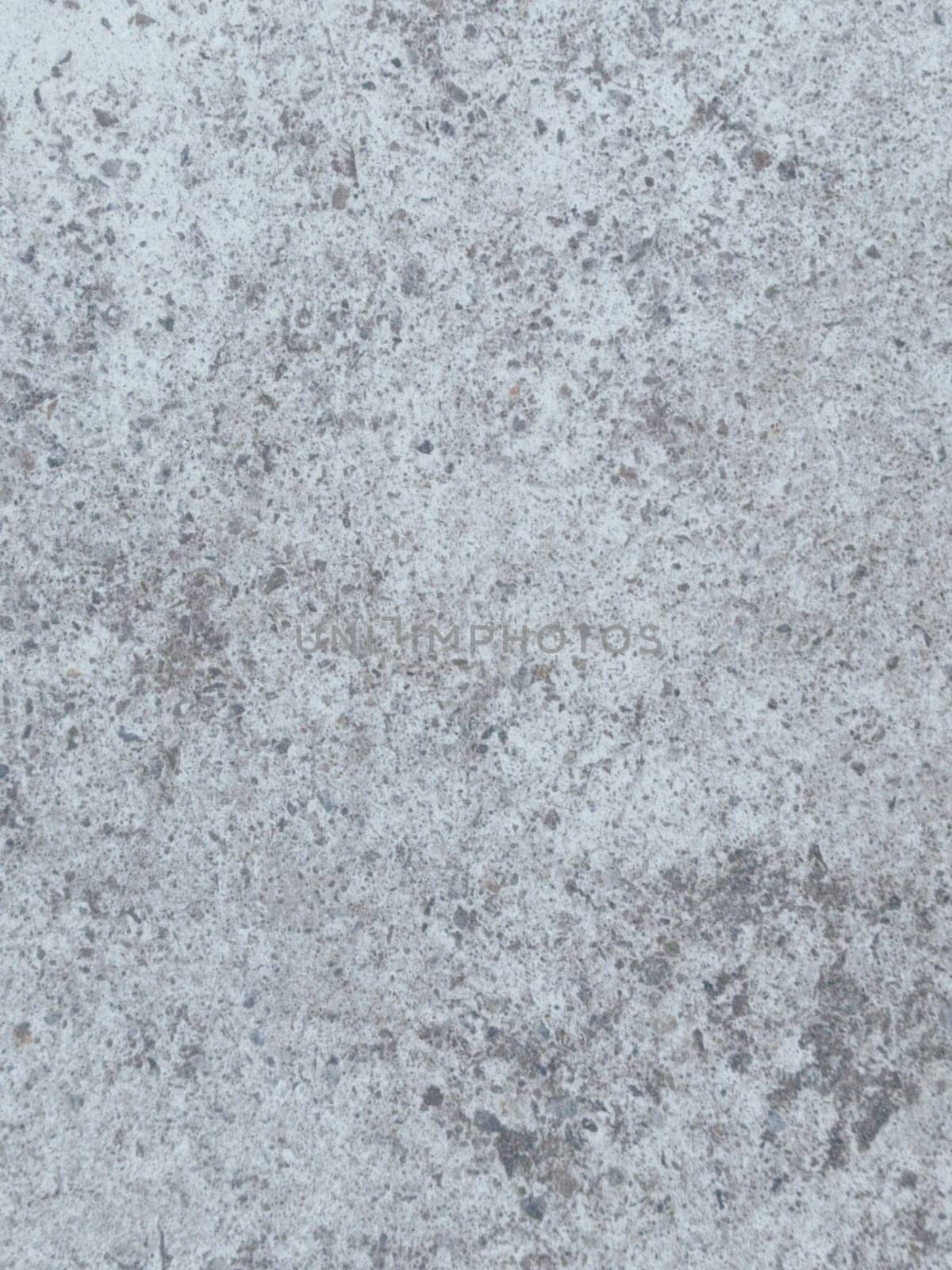 A grey and white wall with a few spots of color. The wall is made of concrete and has a rough texture