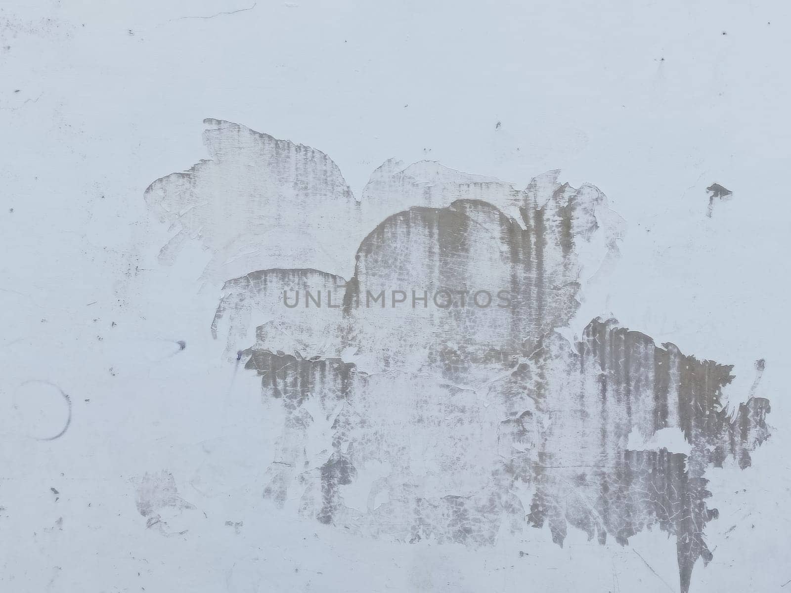 A grey and white wall with a few spots of color. The wall is made of concrete and has a rough texture